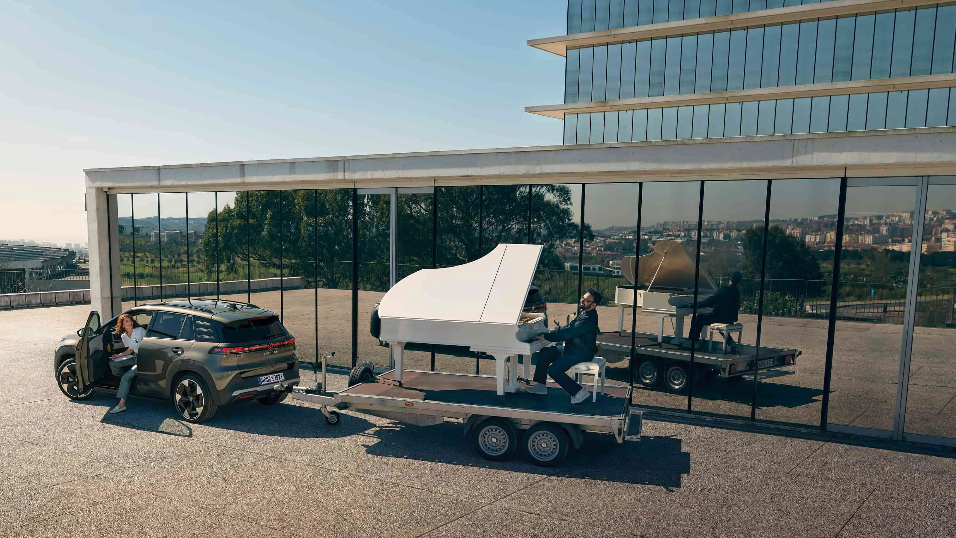 Volkswagen ID. Cross a rebocar um trailer com um homem a tocar piano.