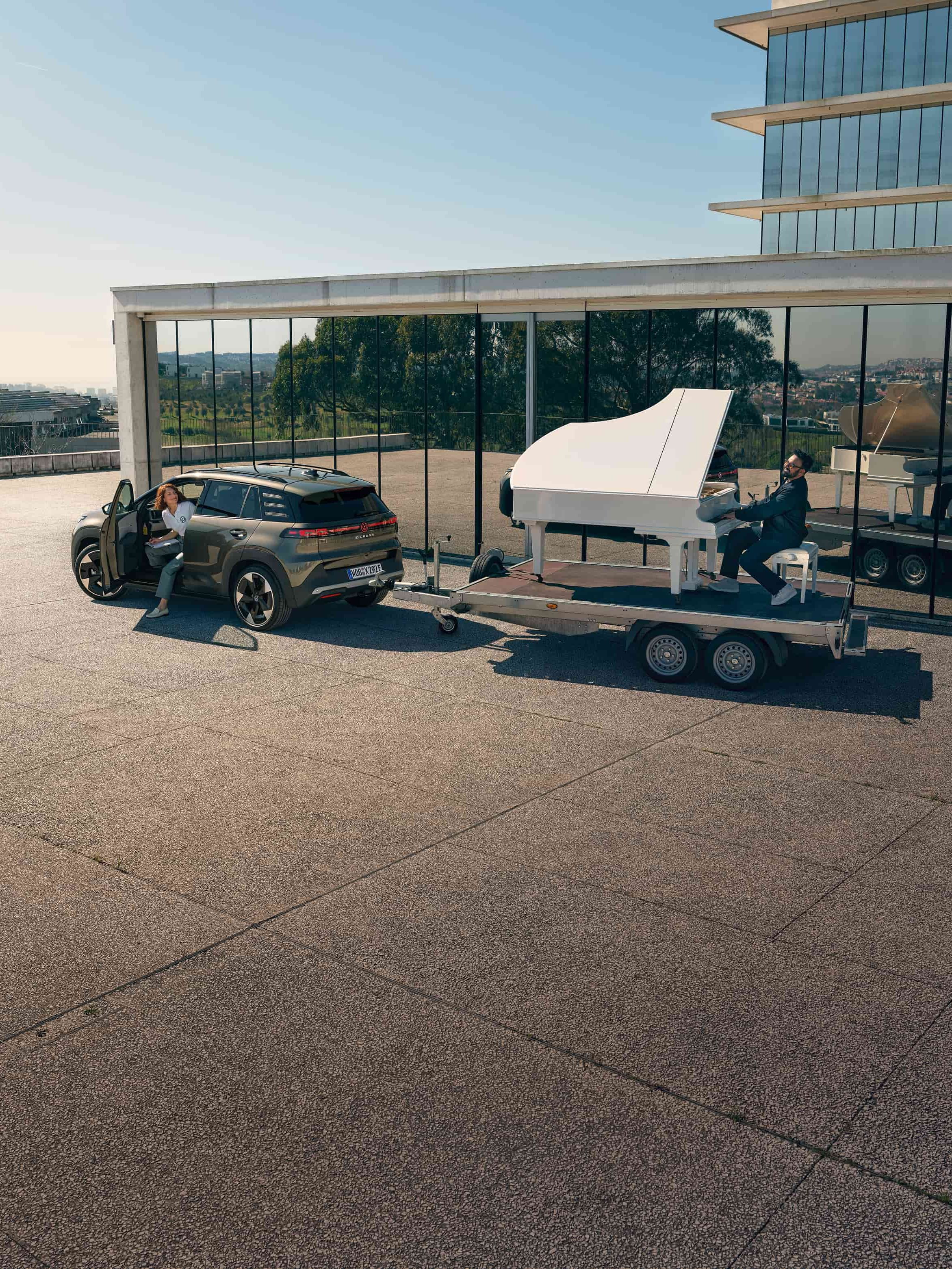 Volkswagen ID. Cross a rebocar um trailer com um homem a tocar piano.