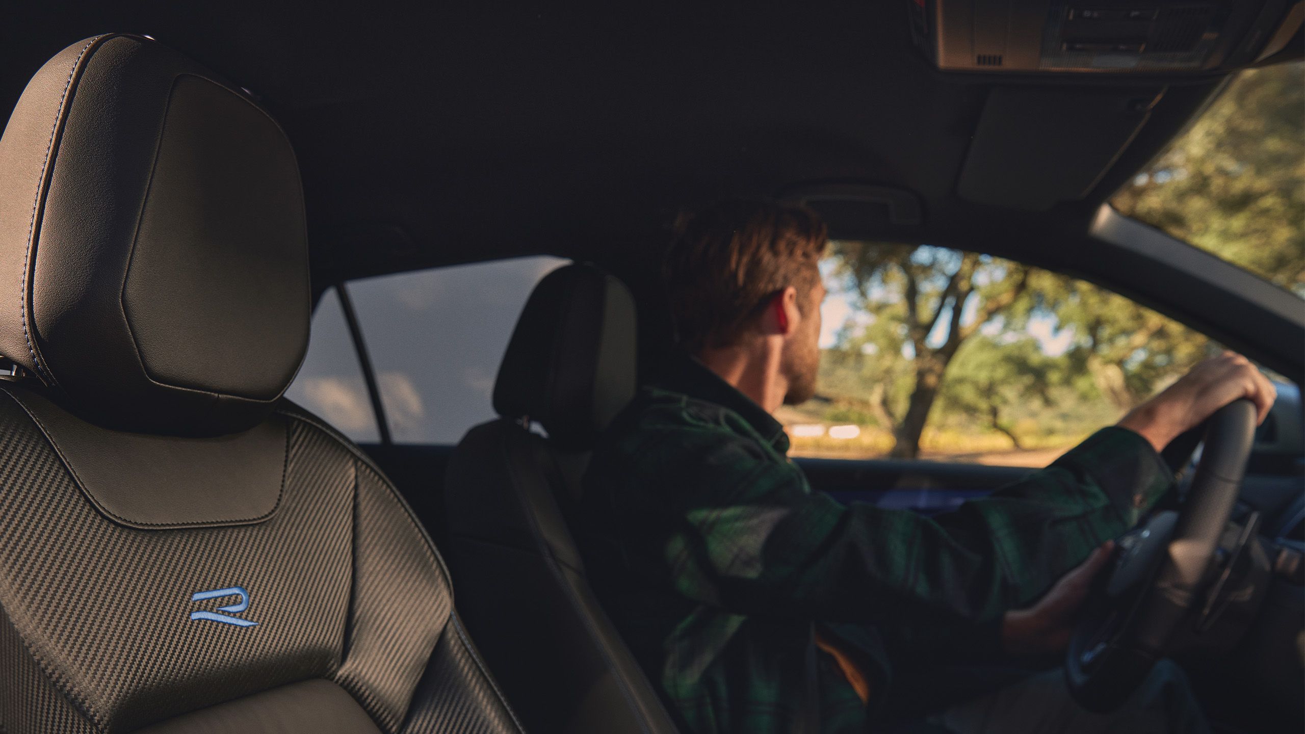 Um homem está ao volante do seu novo VW T-Roc R com bancos desportivos de topo e logótipo R