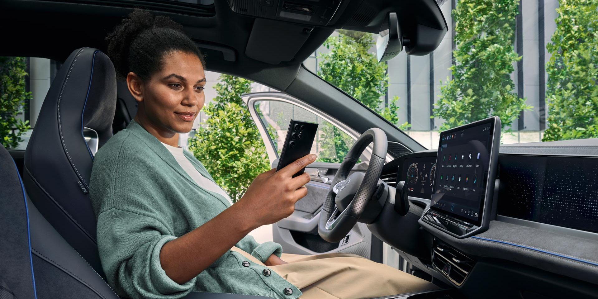 Uma mulher sentada no banco do condutor de um VW Passat estacionado, com a porta aberta, a olhar para o seu smartphone.