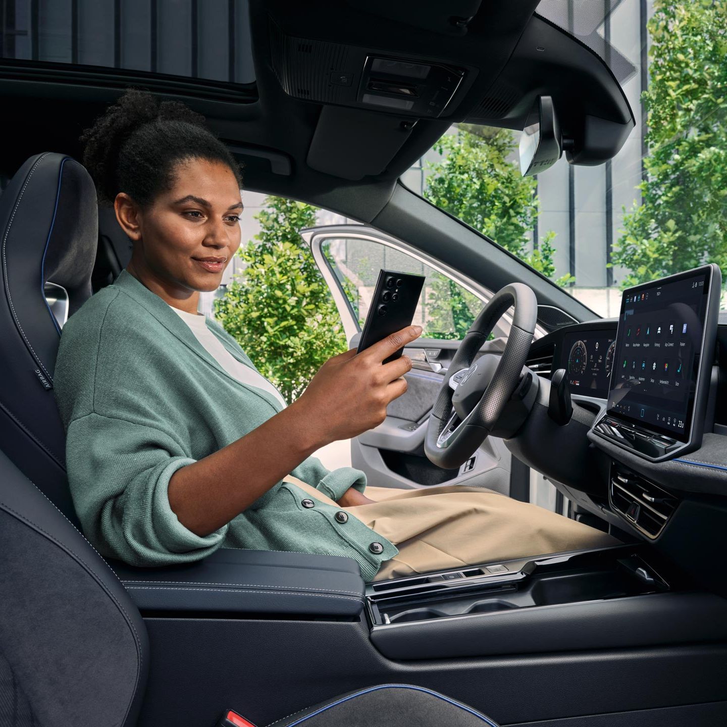 Uma mulher sentada no banco do condutor de um VW Passat estacionado, com a porta aberta, a olhar para o seu smartphone.
