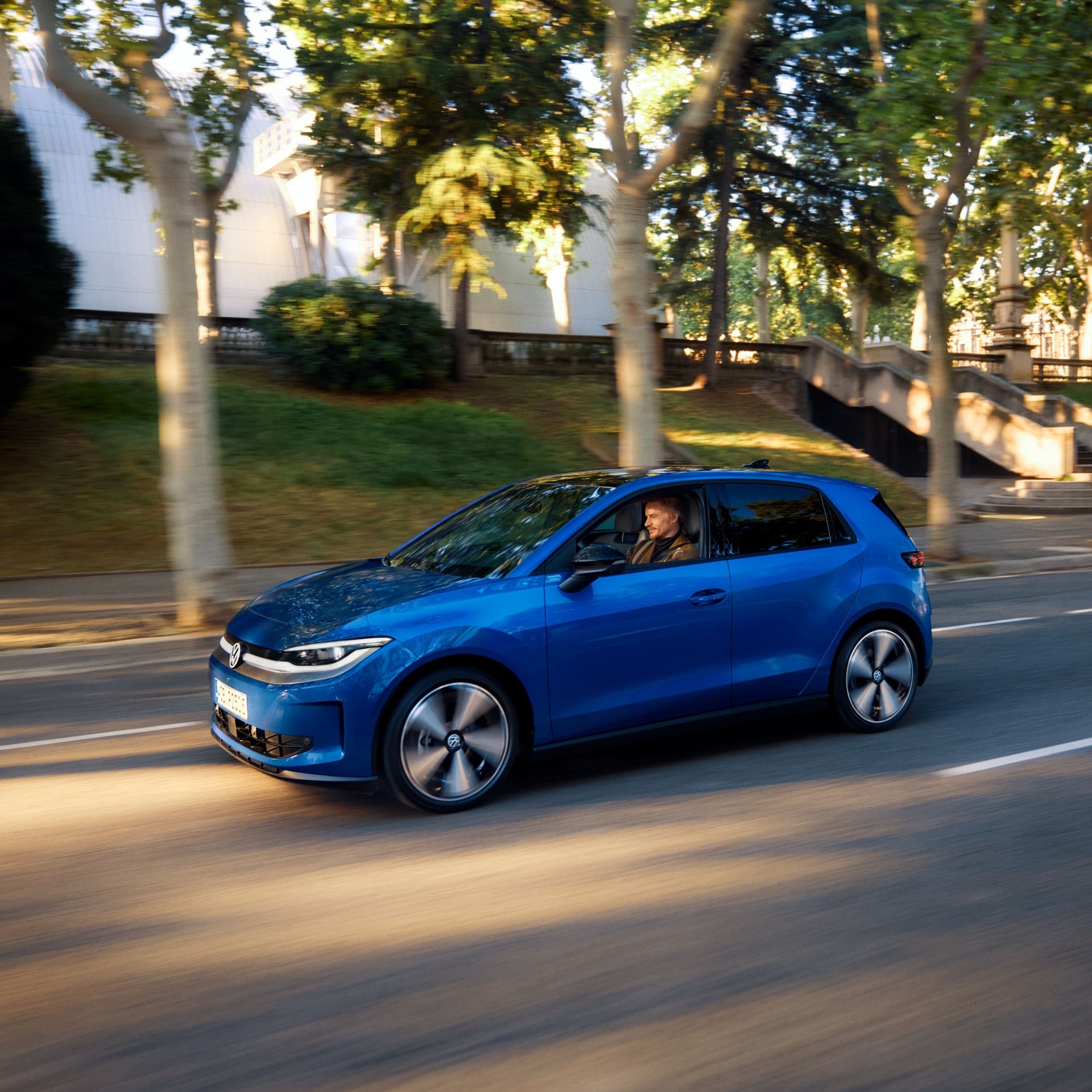 Um VW ID. Polo circula por uma rua, com árvores e casas ao fundo.