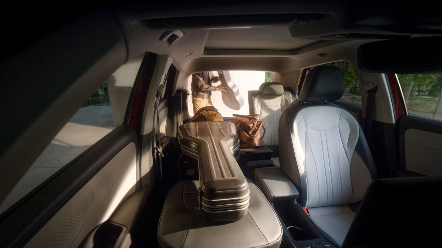 Interior do VW T-Roc Style com banco traseiro rebatido e banco do passageiro totalmente rebatido, sobre o qual está colocada uma mala de guitarra.