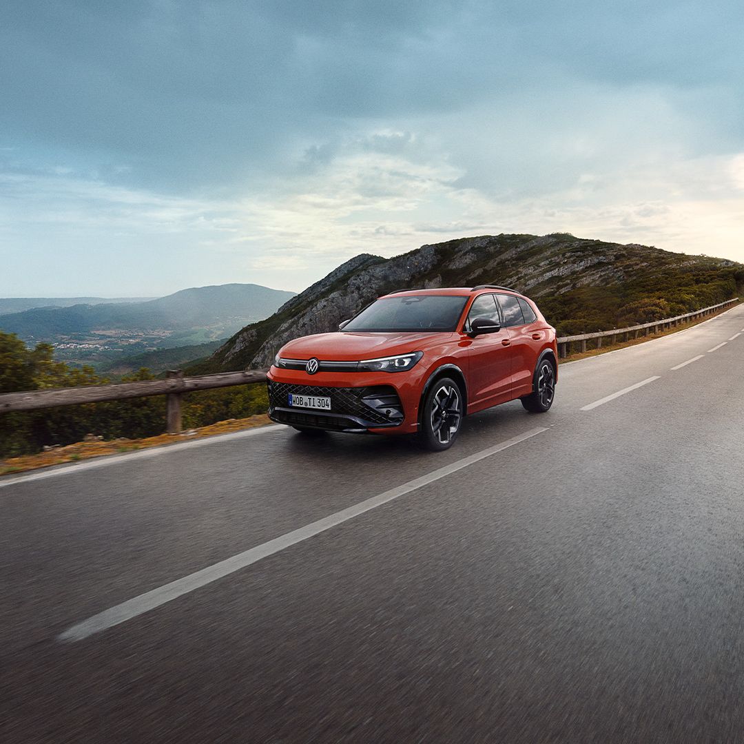 O VW Tiguan vermelho desloca-se ao longo de uma estrada.