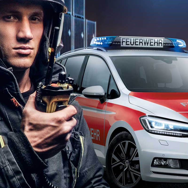 Ein VW Servicemitarbeiter vor einem roten Volkswagen mit Dieselmotor und einer geöffneten Motorhaube in einer Werkstatt