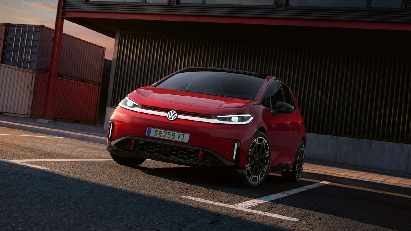 [AI-modified] – Vista frontal de um VW ID.3 GTI vermelho em frente a um edifício com os faróis ligados e o logótipo iluminado.