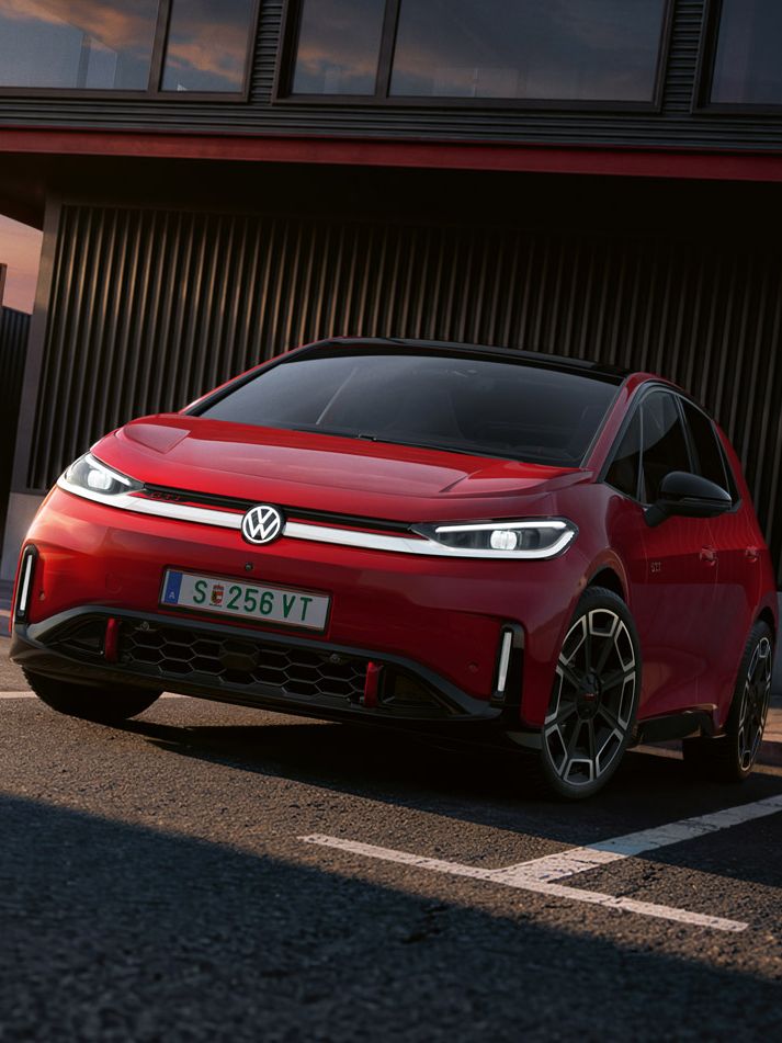 [AI-modified] – Vista frontal de um VW ID.3 GTI vermelho em frente a um edifício com os faróis ligados e o logótipo iluminado.