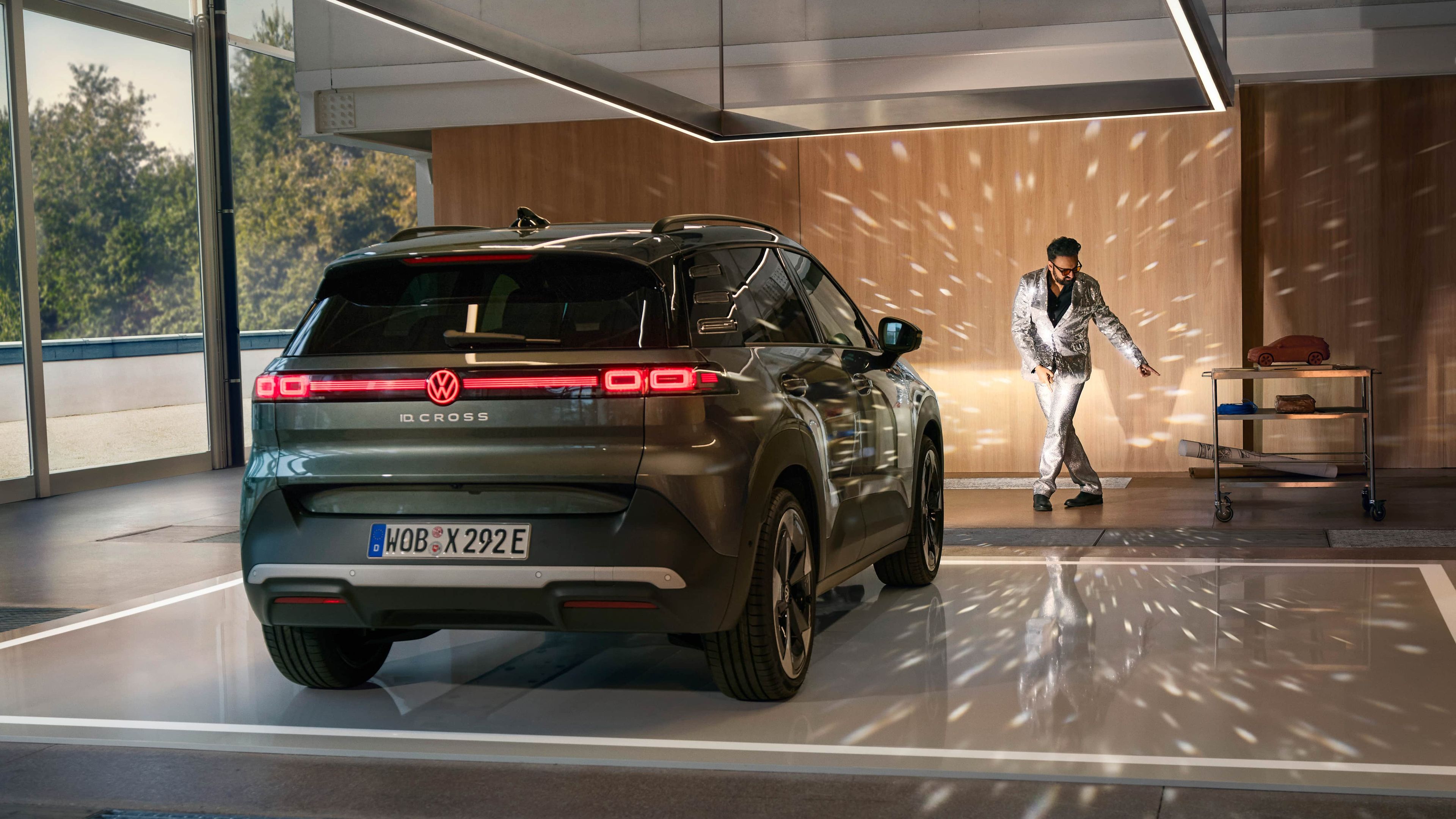 Volkswagen ID. Cross preto estacionado numa garagem moderna com reflexos de luzes tipo bola de espelho e um homem a dançar