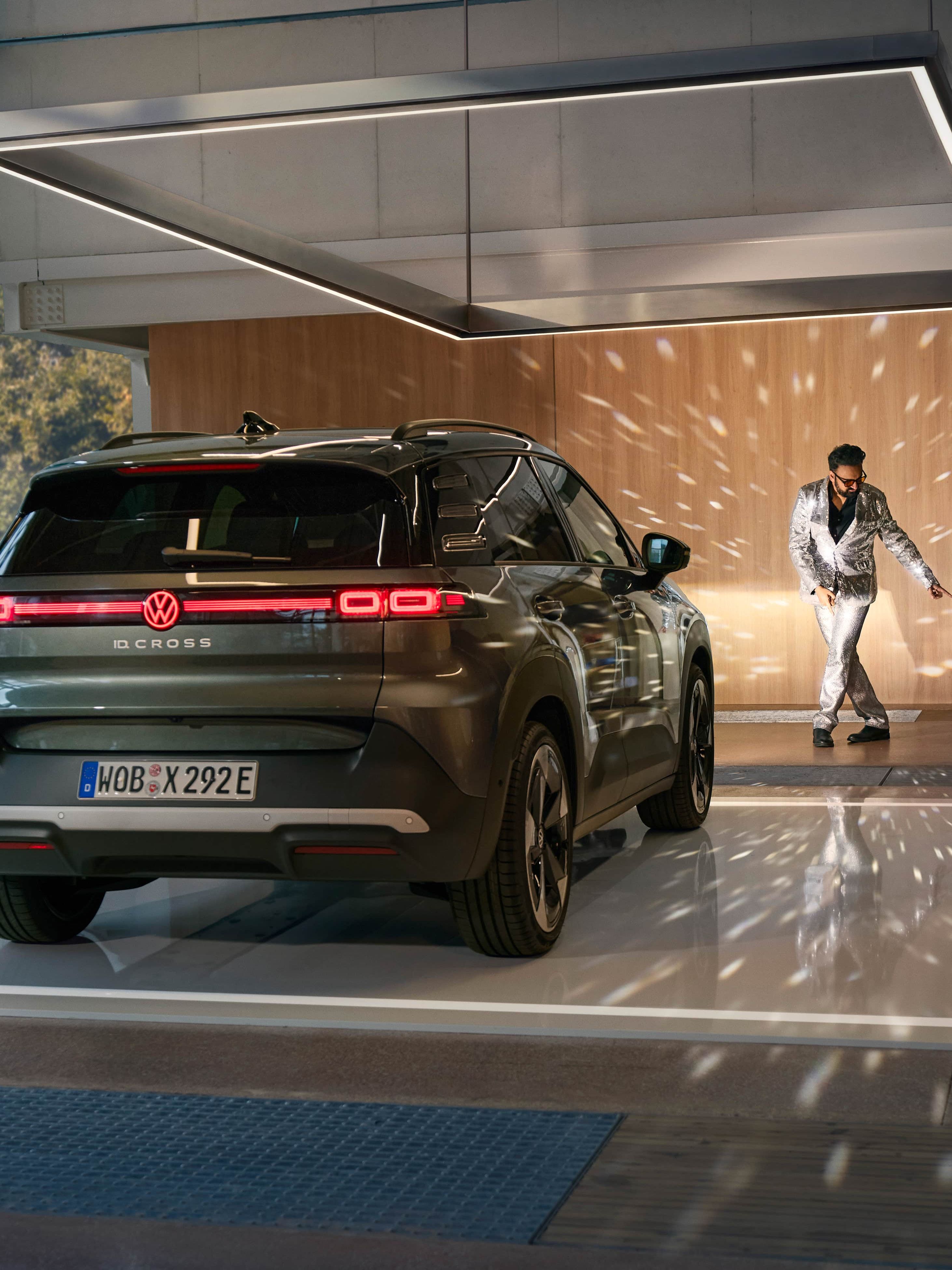 Volkswagen ID. Cross preto estacionado numa garagem moderna com reflexos de luzes tipo bola de espelho e um homem a dançar