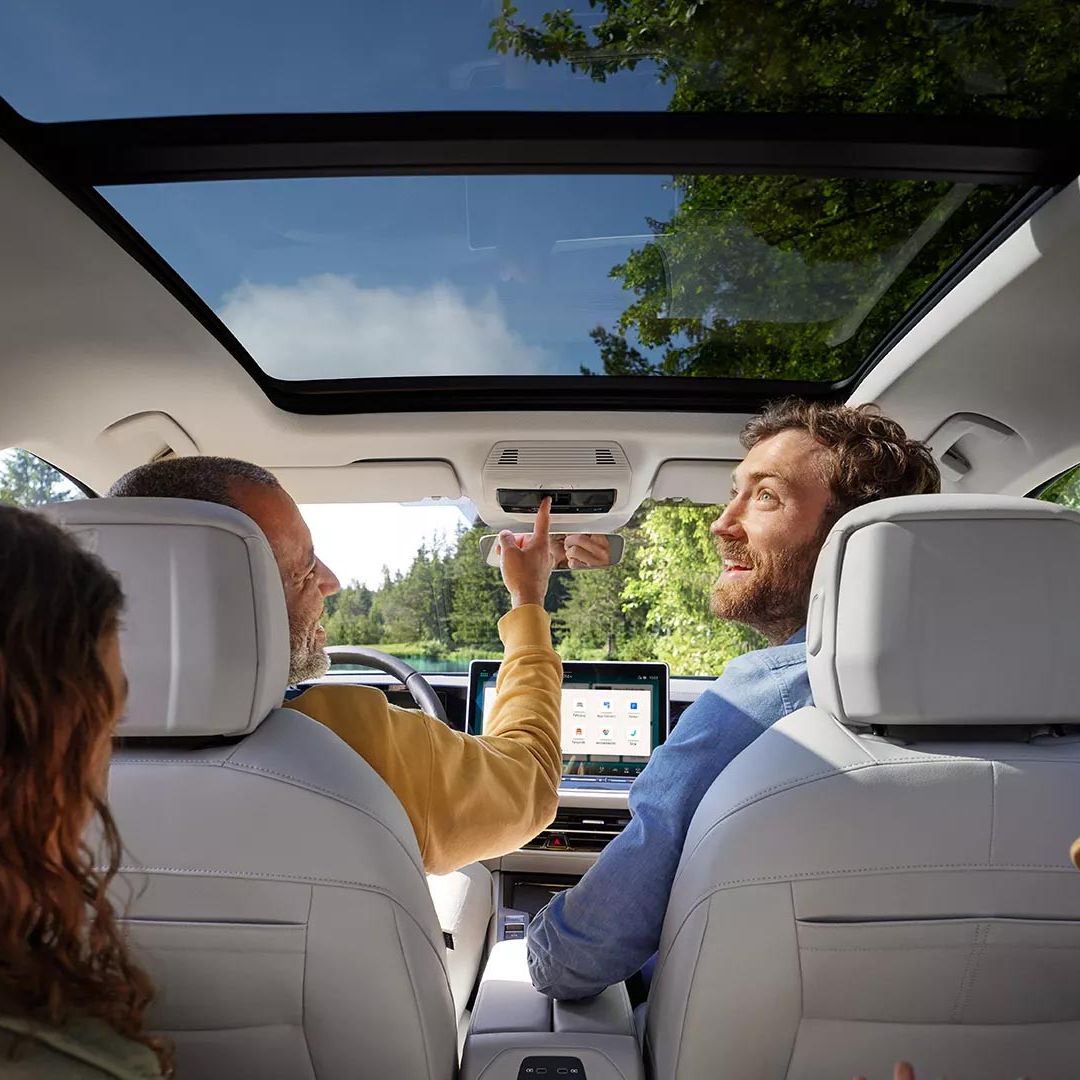 Interior do VW Passat com duas crianças e dois homens a bordo: Vista do banco traseiro para os bancos dianteiros e para o teto de abrir/correr panorâmico opcional.