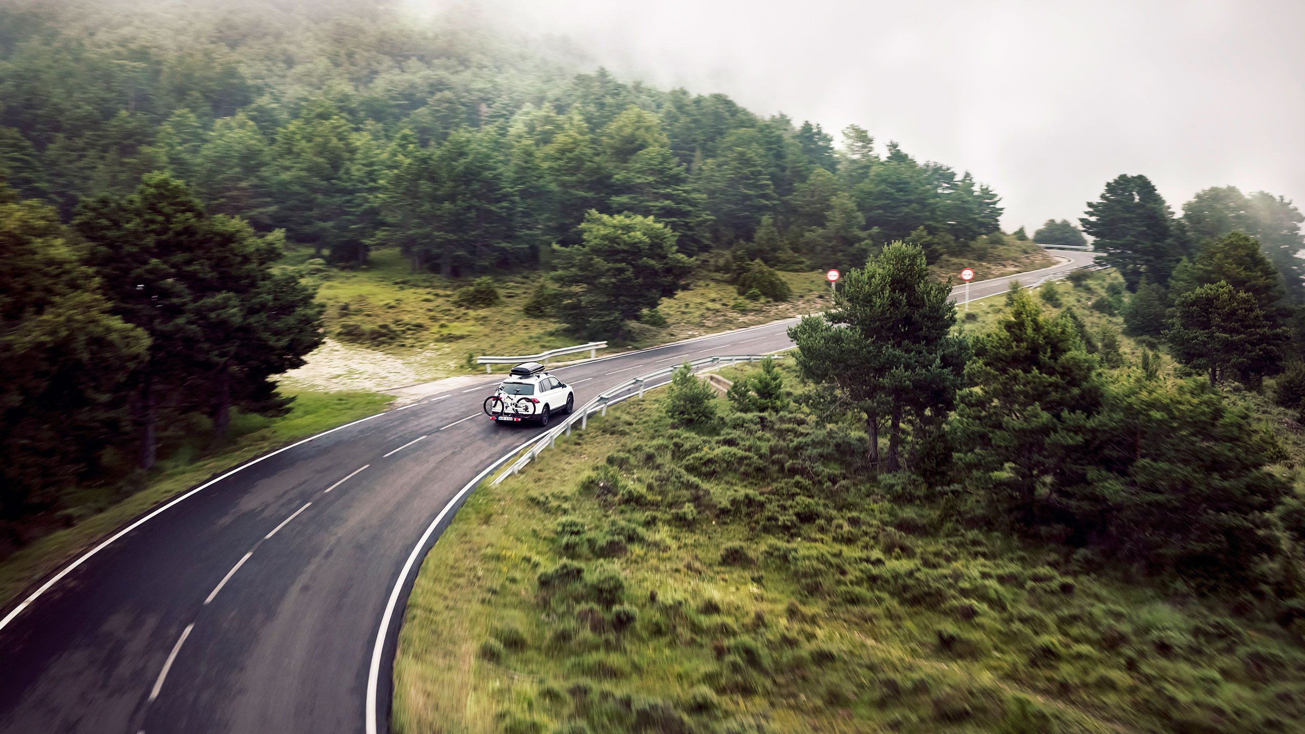 Volkswagen branco em viagem por uma estrada rodeada de vegetação