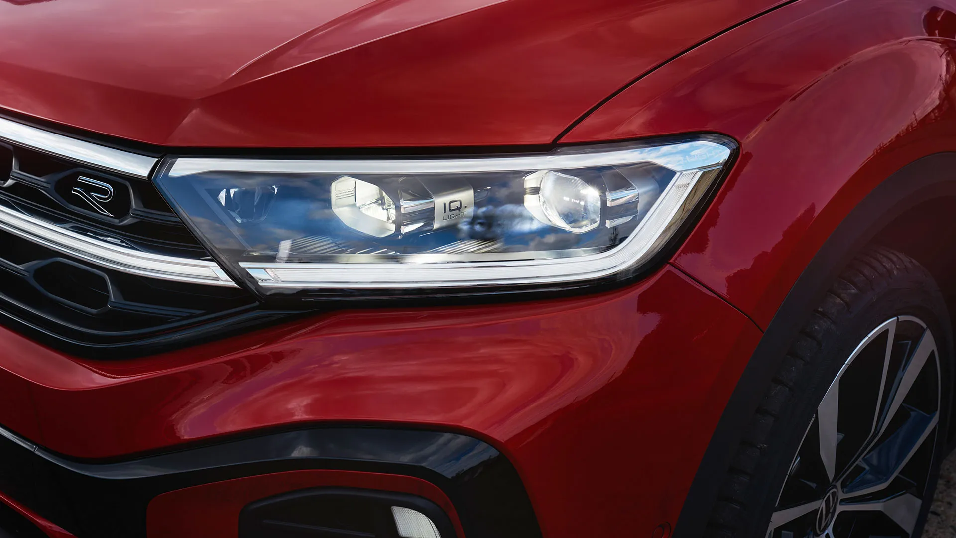 Detalhe do farol dianteiro IQ.LIGHT, do lado direito do VW T-Roc Cabrio em vermelho.