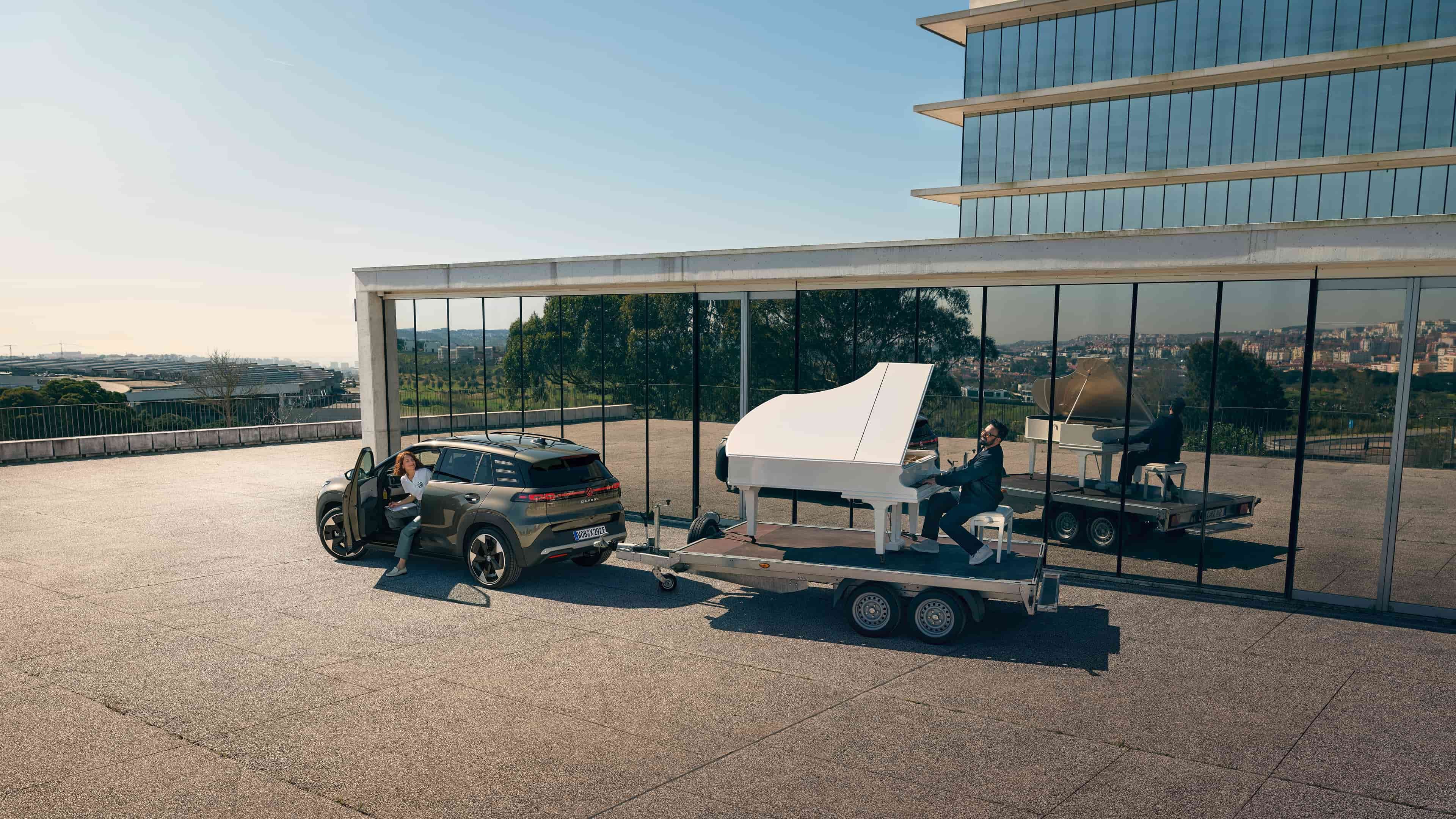 Volkswagen ID. Cross a rebocar um trailer com um homem a tocar piano.