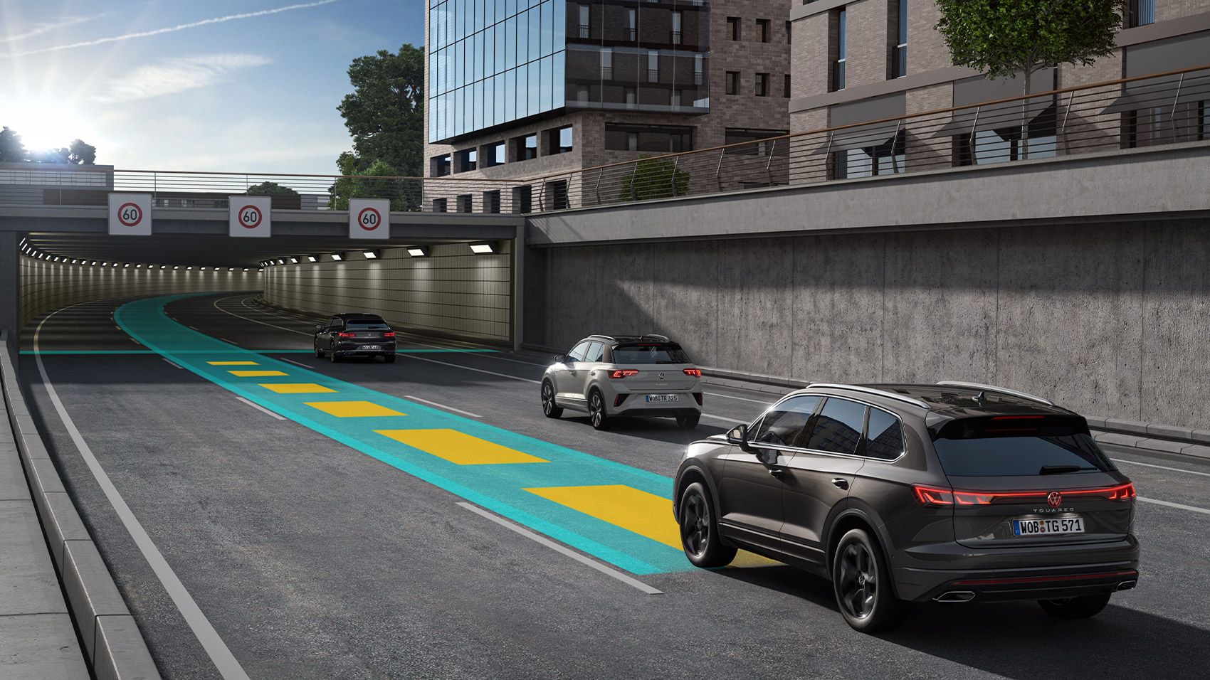 Um VW Touareg cinzento escuro segue ao longo de uma estrada em direção a um túnel sobre uma linha verde e amarela.