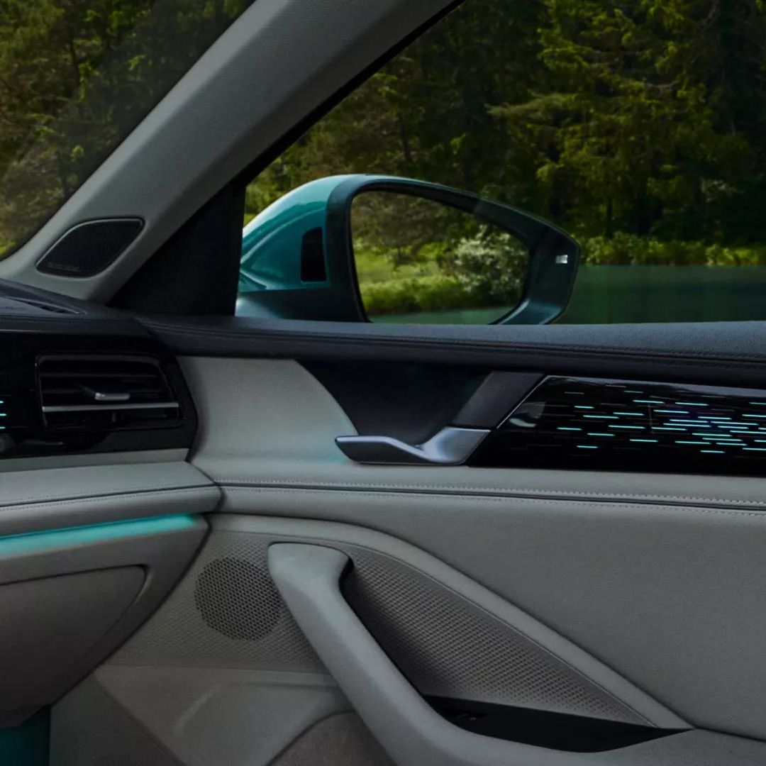 Vista interior do VW Passat com estofos dos bancos em couro de cor clara, iluminação ambiente em azul e o grande visor.