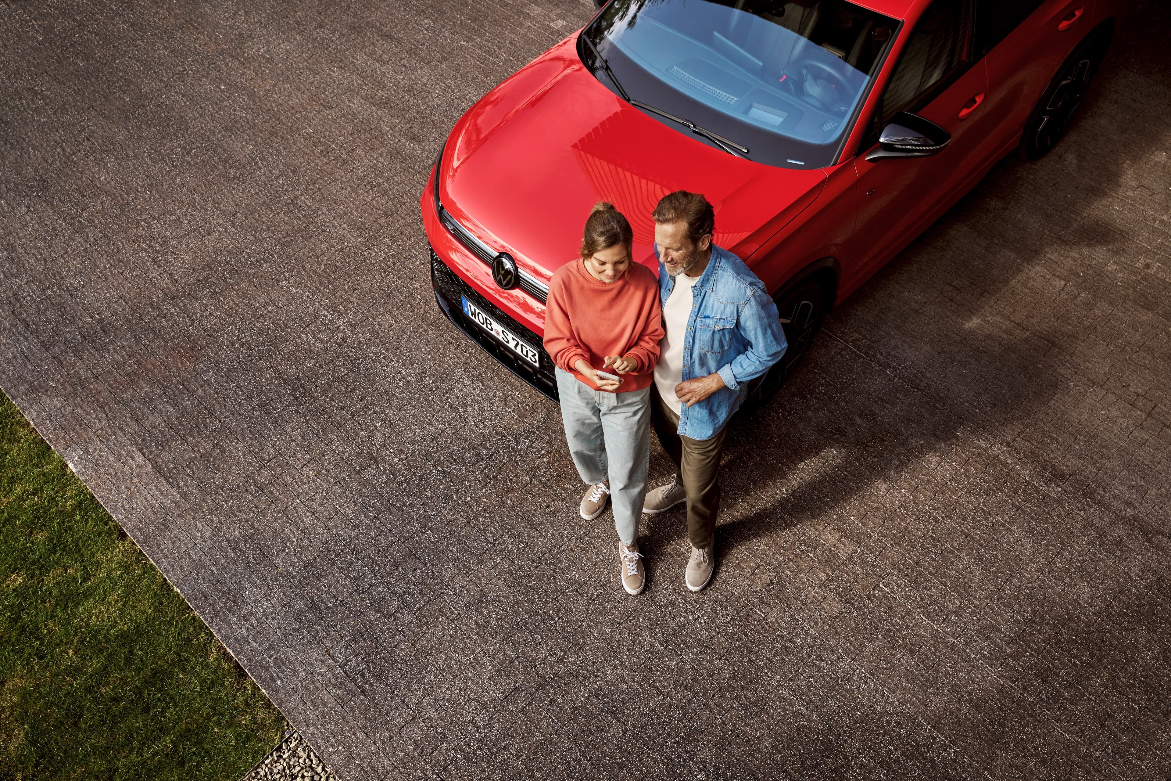 Duas pessoas fora de um Volkswagen a mexer no telemóvel