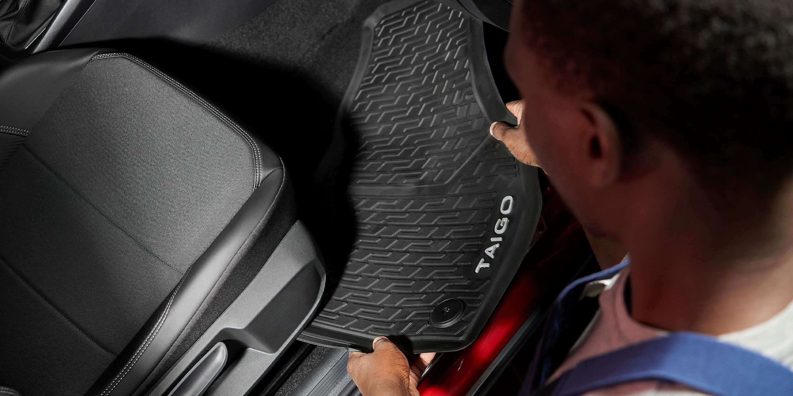 Um funcionário da Volkswagen coloca um tapete de borracha com letras Taigo em um Volkswagen.