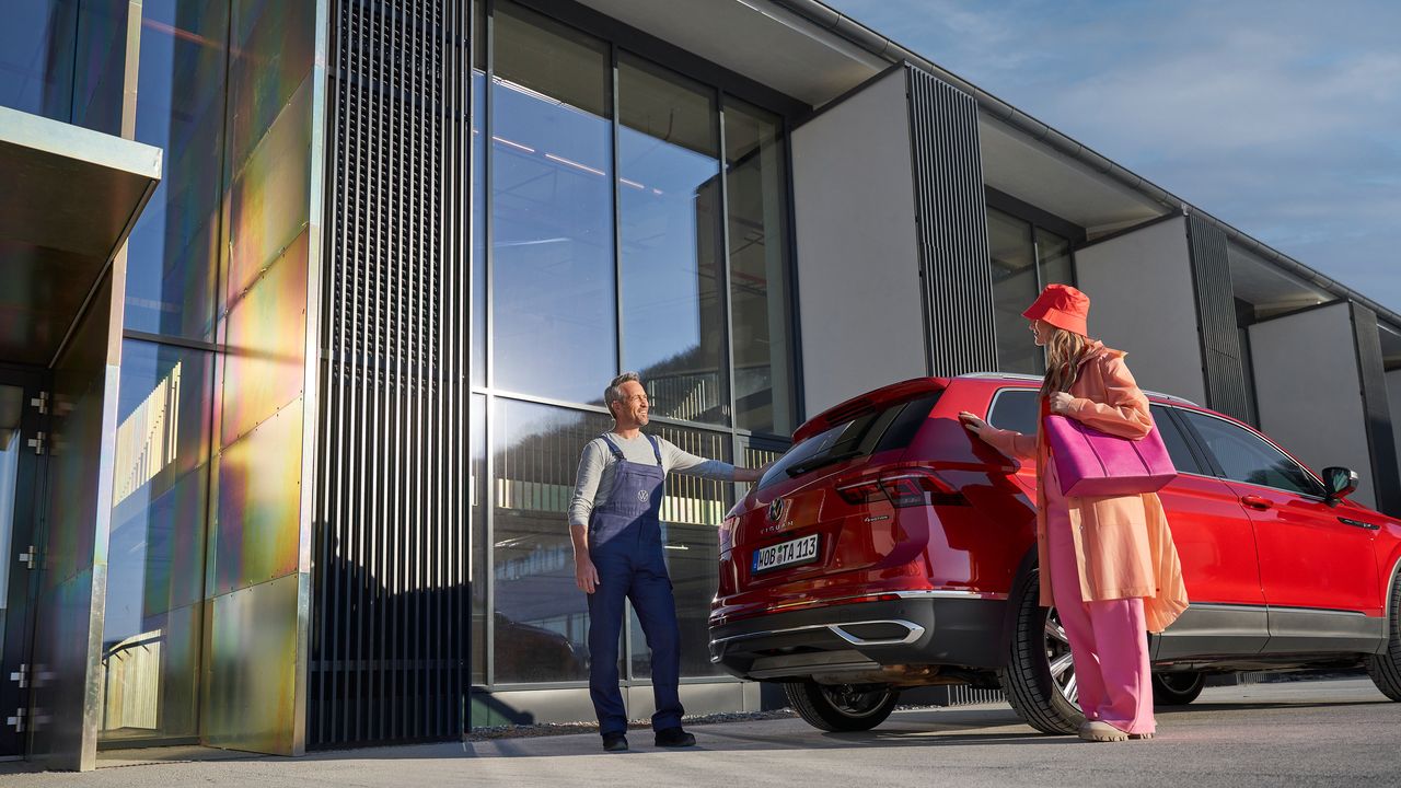 Um funcionário da VW verifica os fluidos de um veículo VW amarelo durante o controlo do veículo numa oficina.