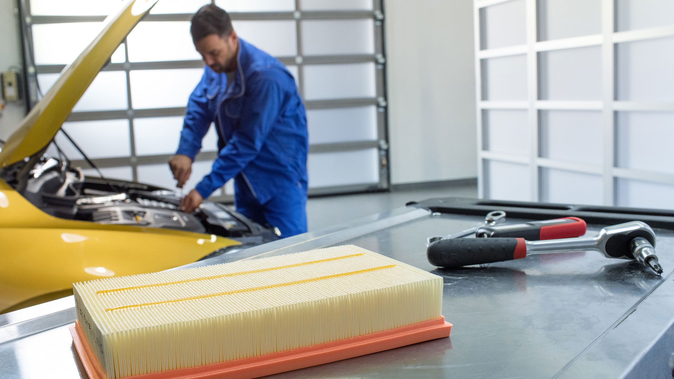 Um empregado de serviço da VW verifica o óleo enquanto a inspeção é feita num VW Golf amarelo