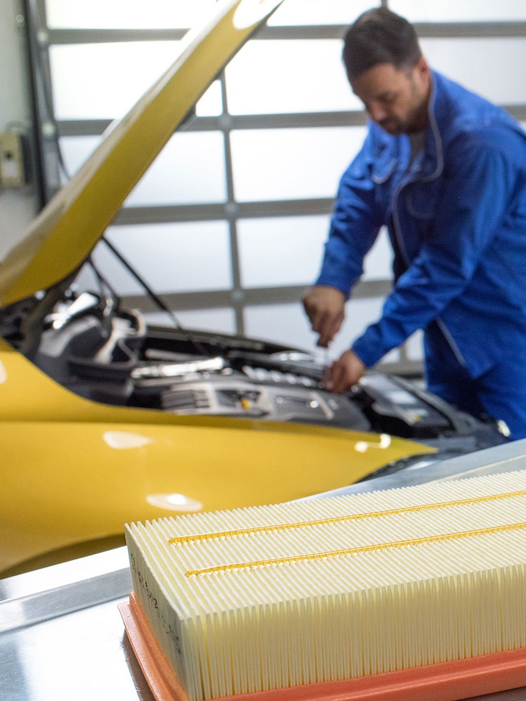 Um empregado de serviço da VW verifica o óleo enquanto a inspeção é feita num VW Golf amarelo
