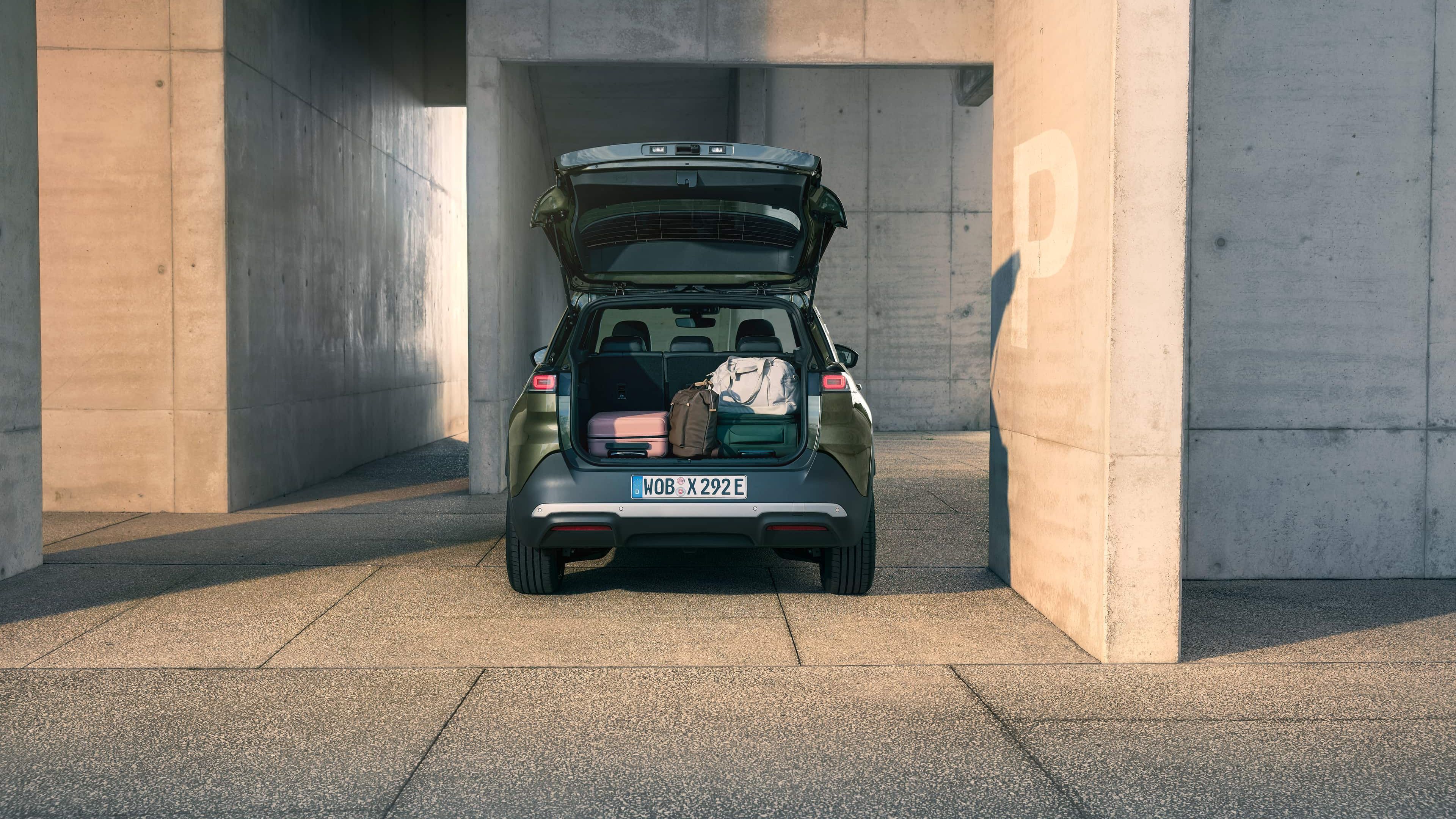 Um VW ID. Cross verde em vista traseira com a tampa da bagageira aberta e bagagens no seu interior.
