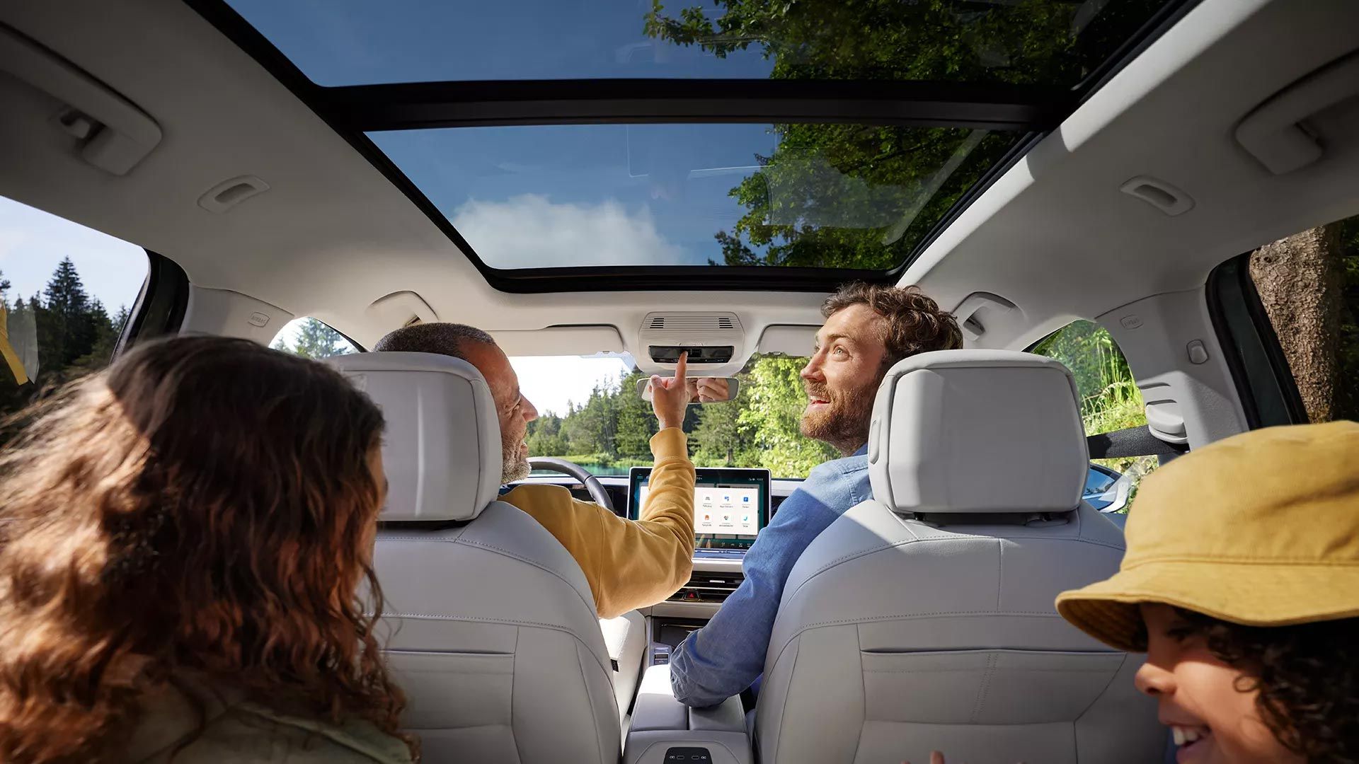 Interior do VW Passat com duas crianças e dois homens a bordo: Vista do banco traseiro para os bancos dianteiros e para o teto de abrir/correr panorâmico opcional.