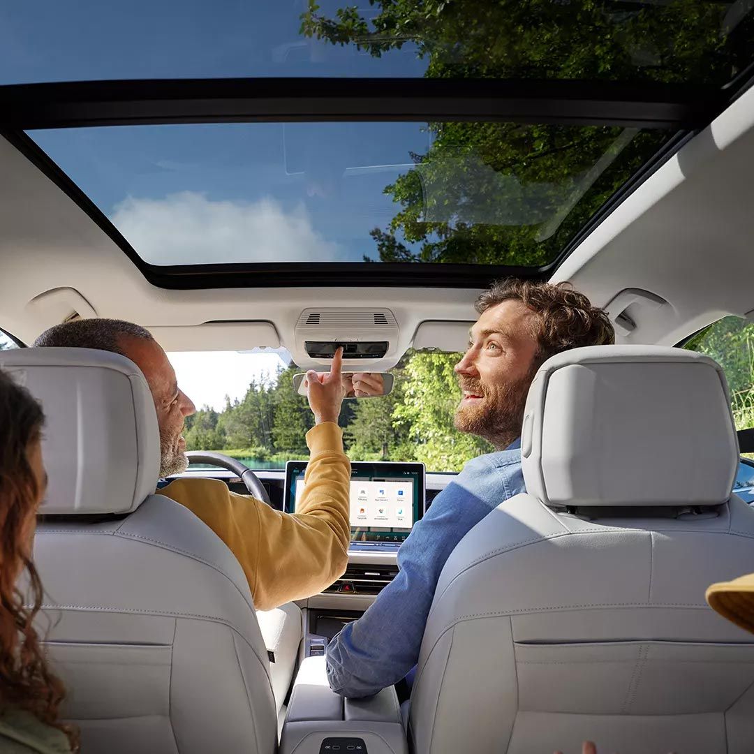 Interior do VW Passat com duas crianças e dois homens a bordo: Vista do banco traseiro para os bancos dianteiros e para o teto de abrir/correr panorâmico opcional.