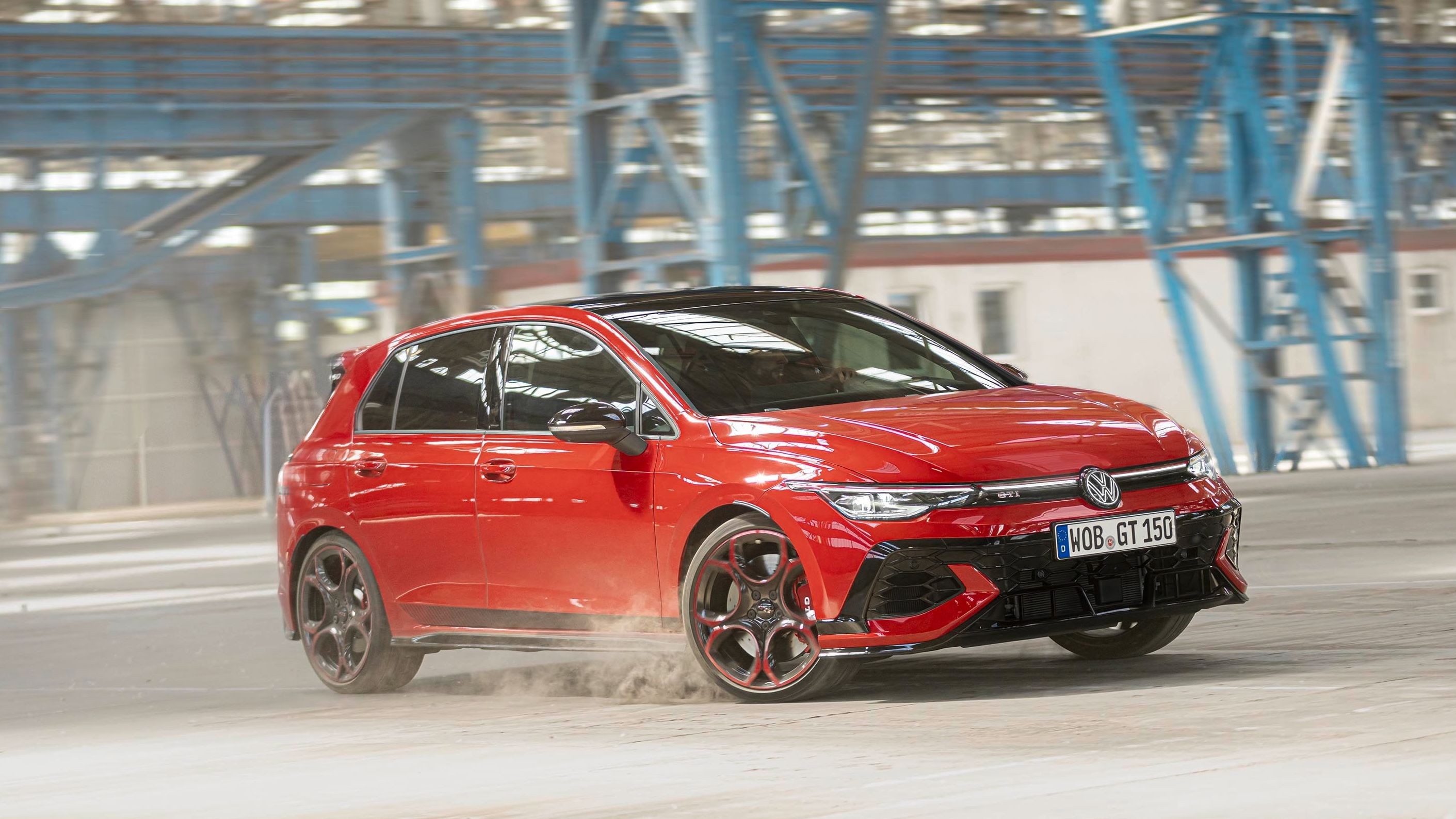 Um VW Golf GTI EDITION 50 vermelho faz uma curva num pavilhão de fábrica.