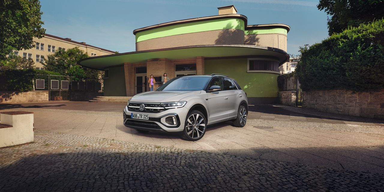 VW T-Roc R-Line em branco em frente de um edifício, veem-se a dianteira e a lateral