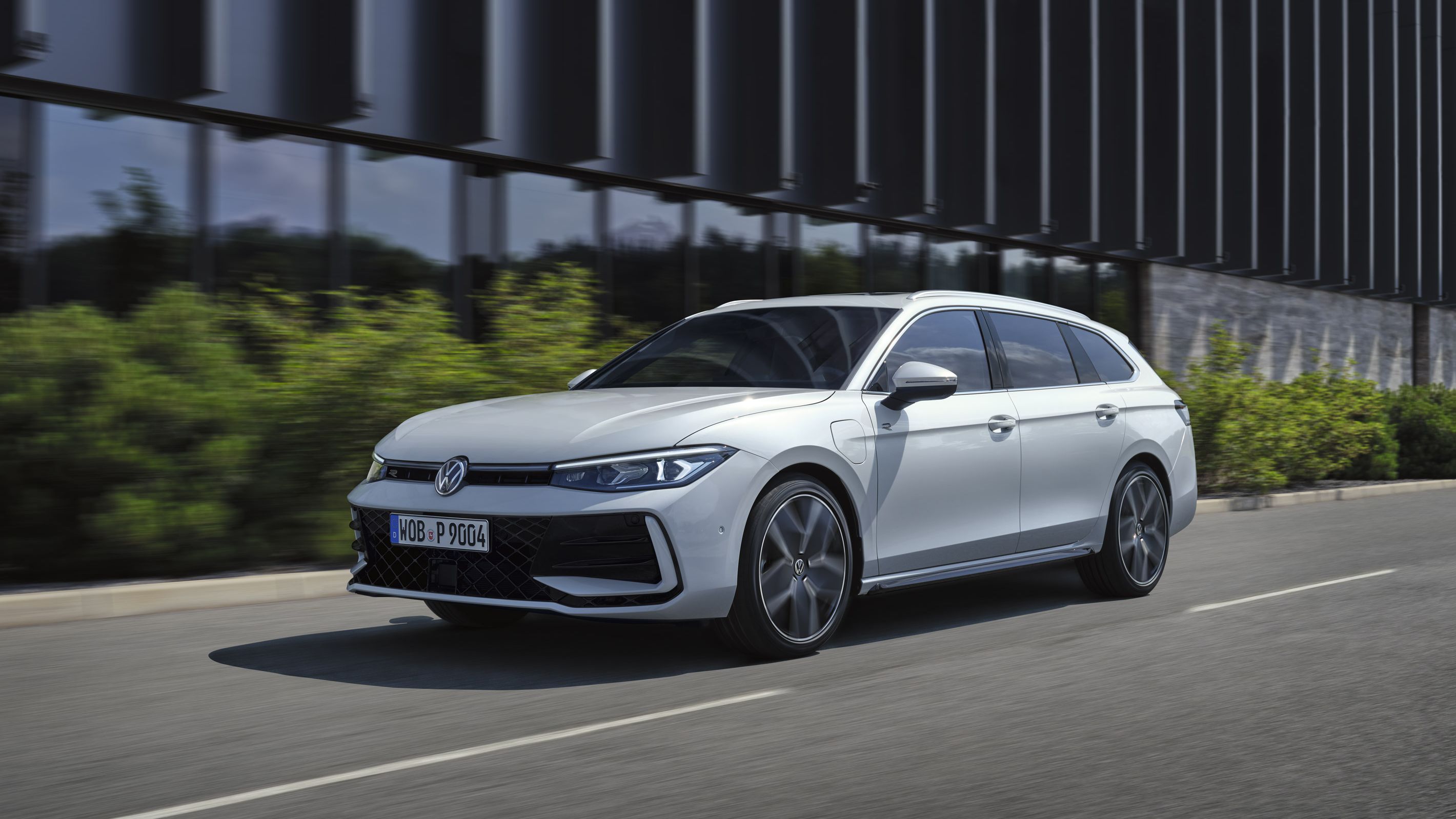 VW Passat em branco passa ao lado de um edifício.