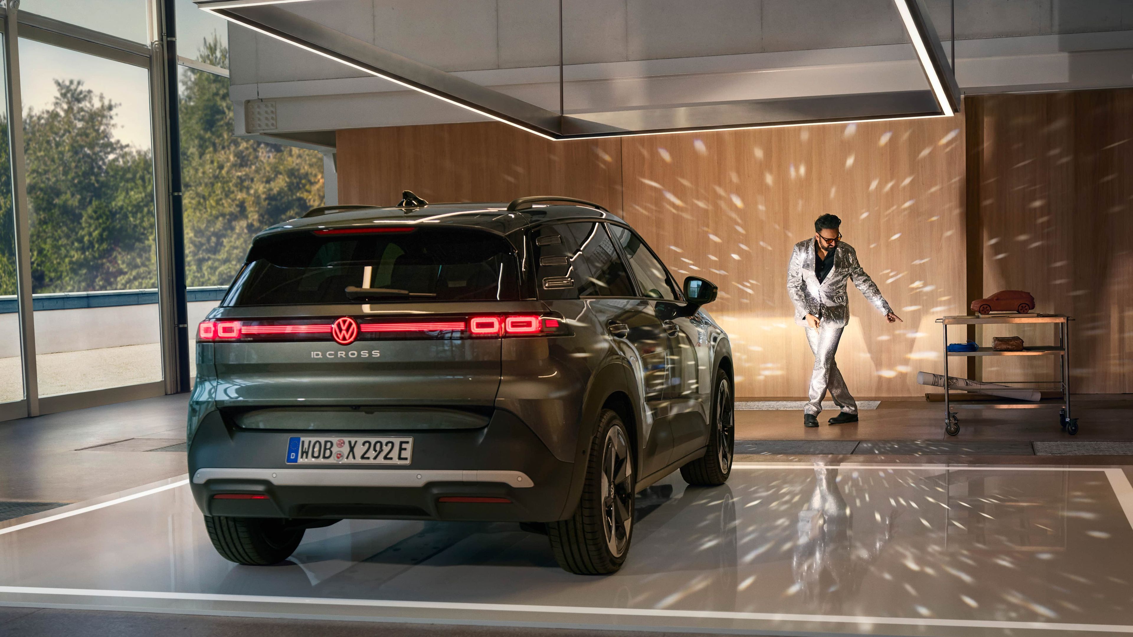 Volkswagen ID. Cross preto estacionado numa garagem moderna com reflexos de luzes tipo bola de espelho e um homem a dançar