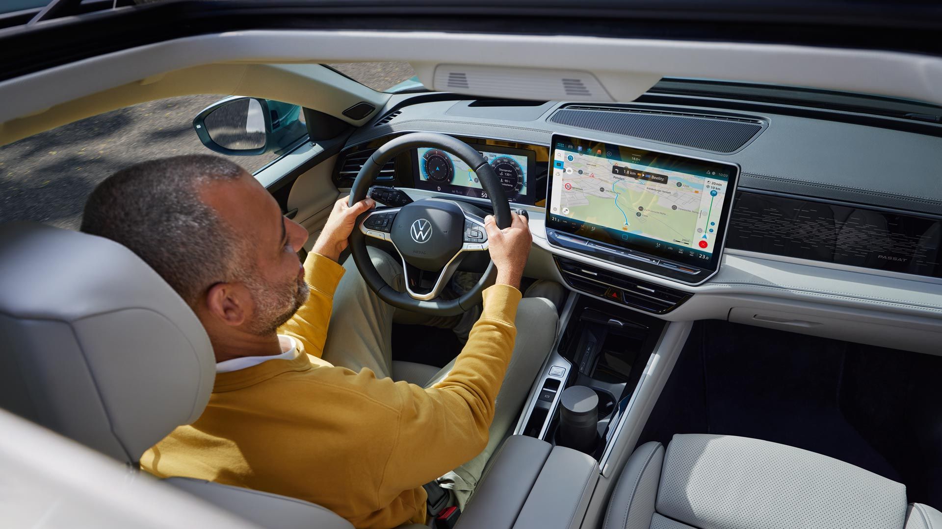 Vista de cima através do teto de abrir opcional do VW Passat, onde um homem está sentado com as duas mãos no volante.