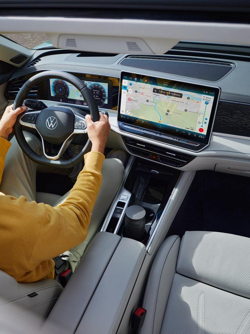 Vista de cima através do teto de abrir opcional do VW Passat, onde um homem está sentado com as duas mãos no volante.