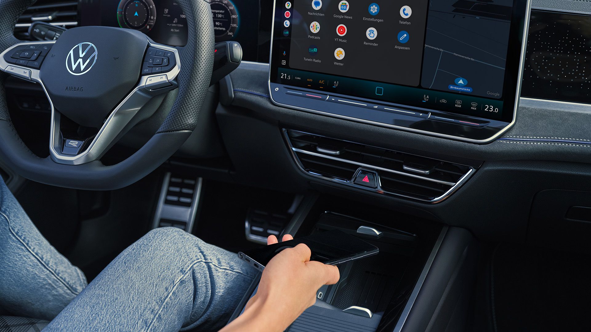 Vista detalhada do cockpit do VW Passat. Uma pessoa no banco do condutor segura um smartphone na mão.