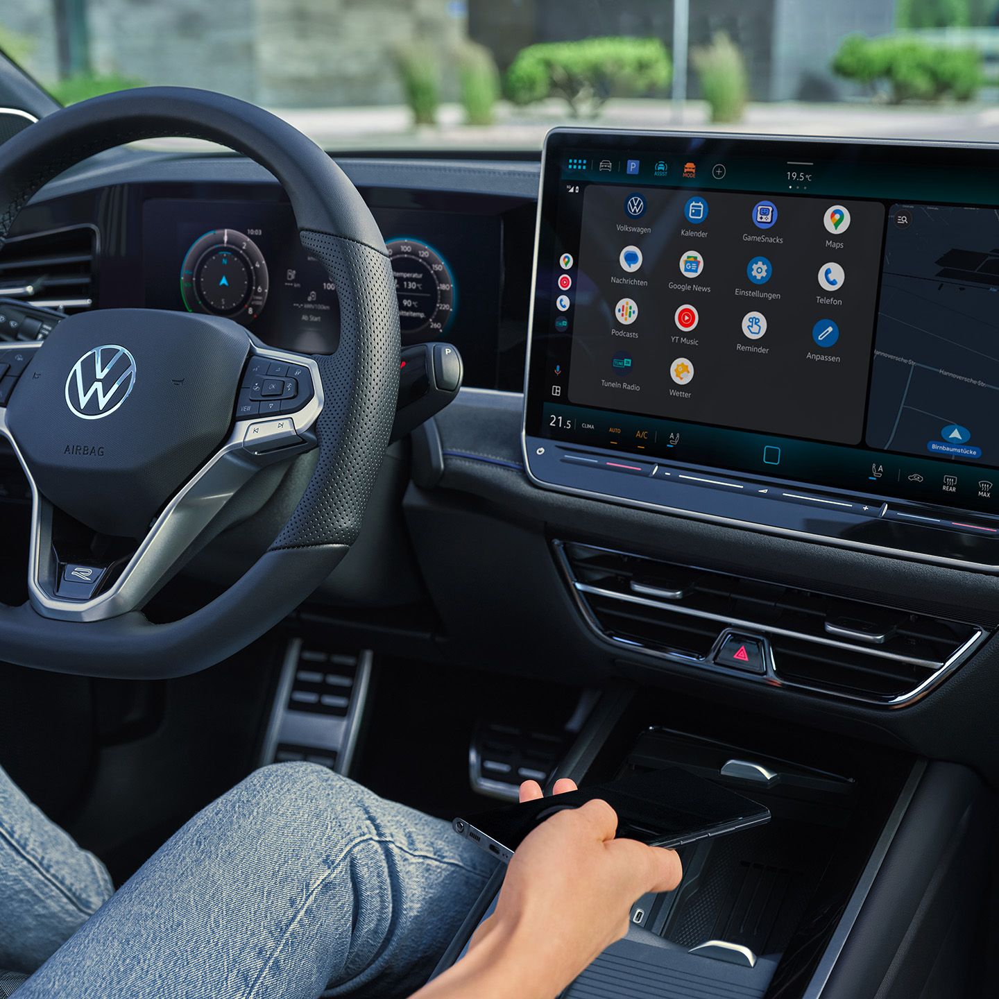 Vista detalhada do cockpit do VW Passat. Uma pessoa no banco do condutor segura um smartphone na mão.