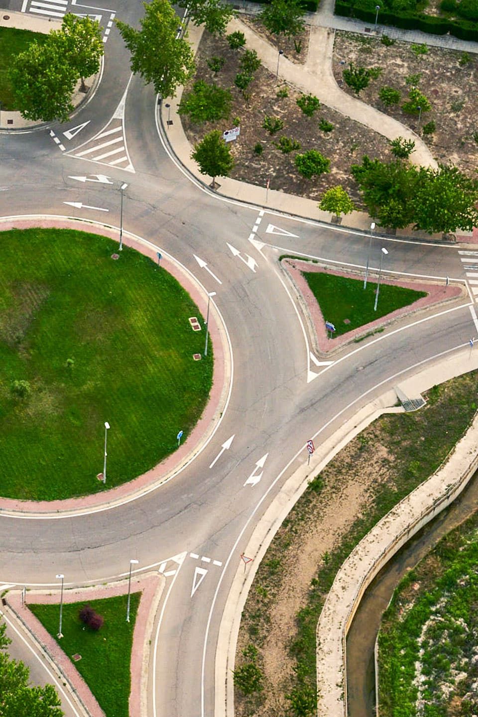 Imagem de uma rotunda vista de cima, rodeada por árvores e áreas verdes.  