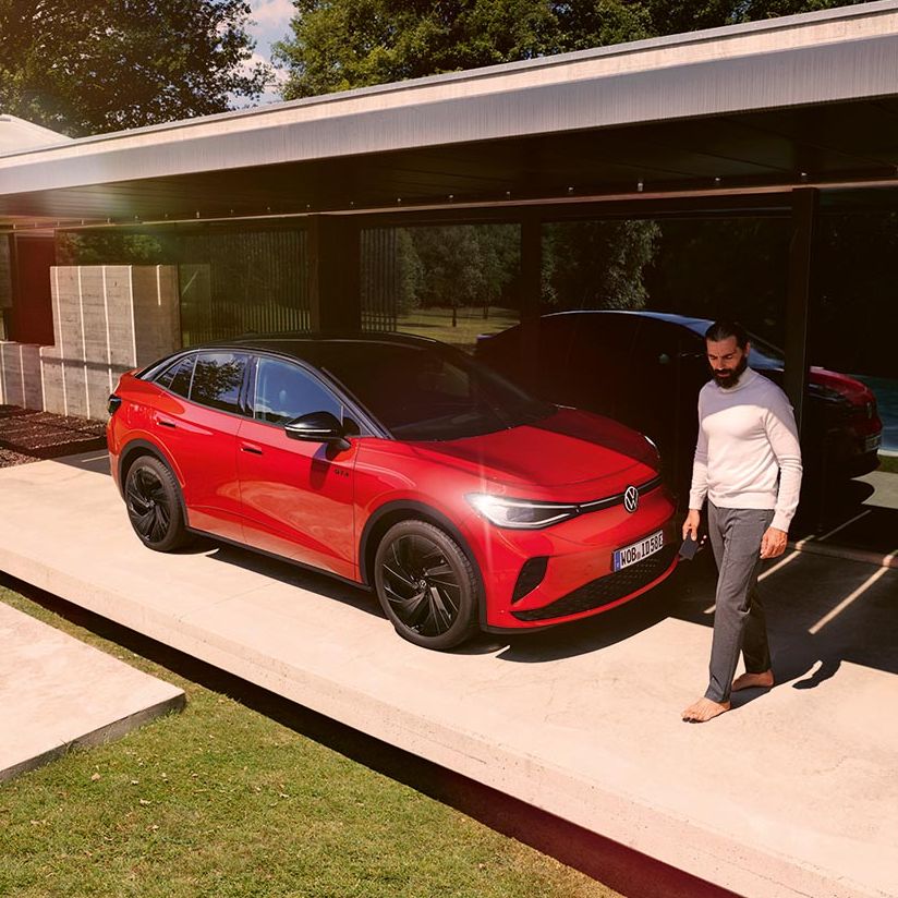 Exterior de um VW ID.5 GTX vermelho e um homem em frente ao veículo.