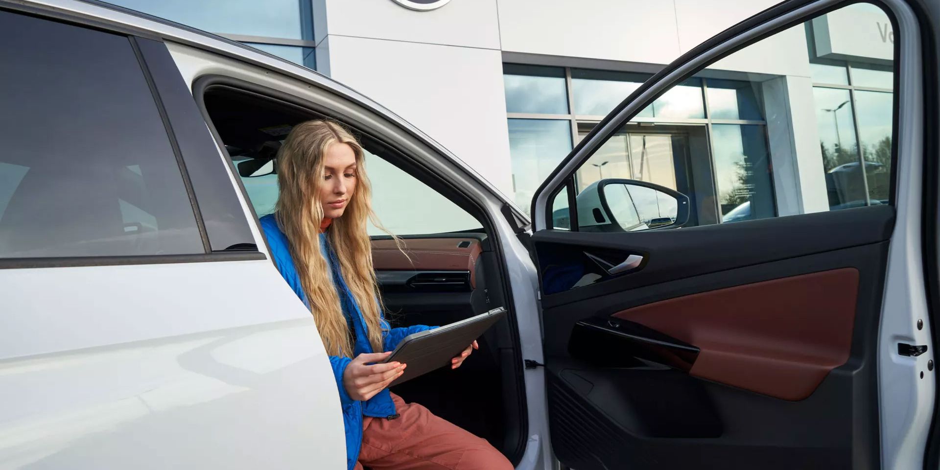 Eine Frau sitzt bei geöffneter Fahrzeugtüre in einem VW ID.