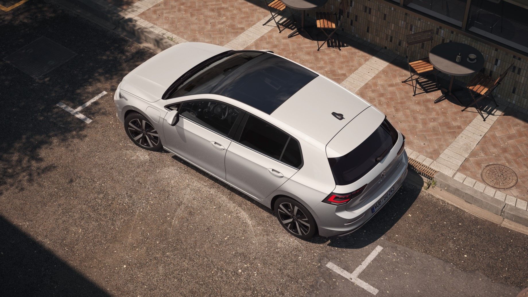 Topview auf einen weißen VW Golf mit Fokus auf das Panoramadach-Aufstell-/Schiebedach. 