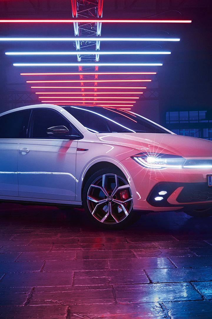 Fotografia de um VW Polo GTI branco, num salão escuro, com os faróis LED ligados, sob elementos luminosos.