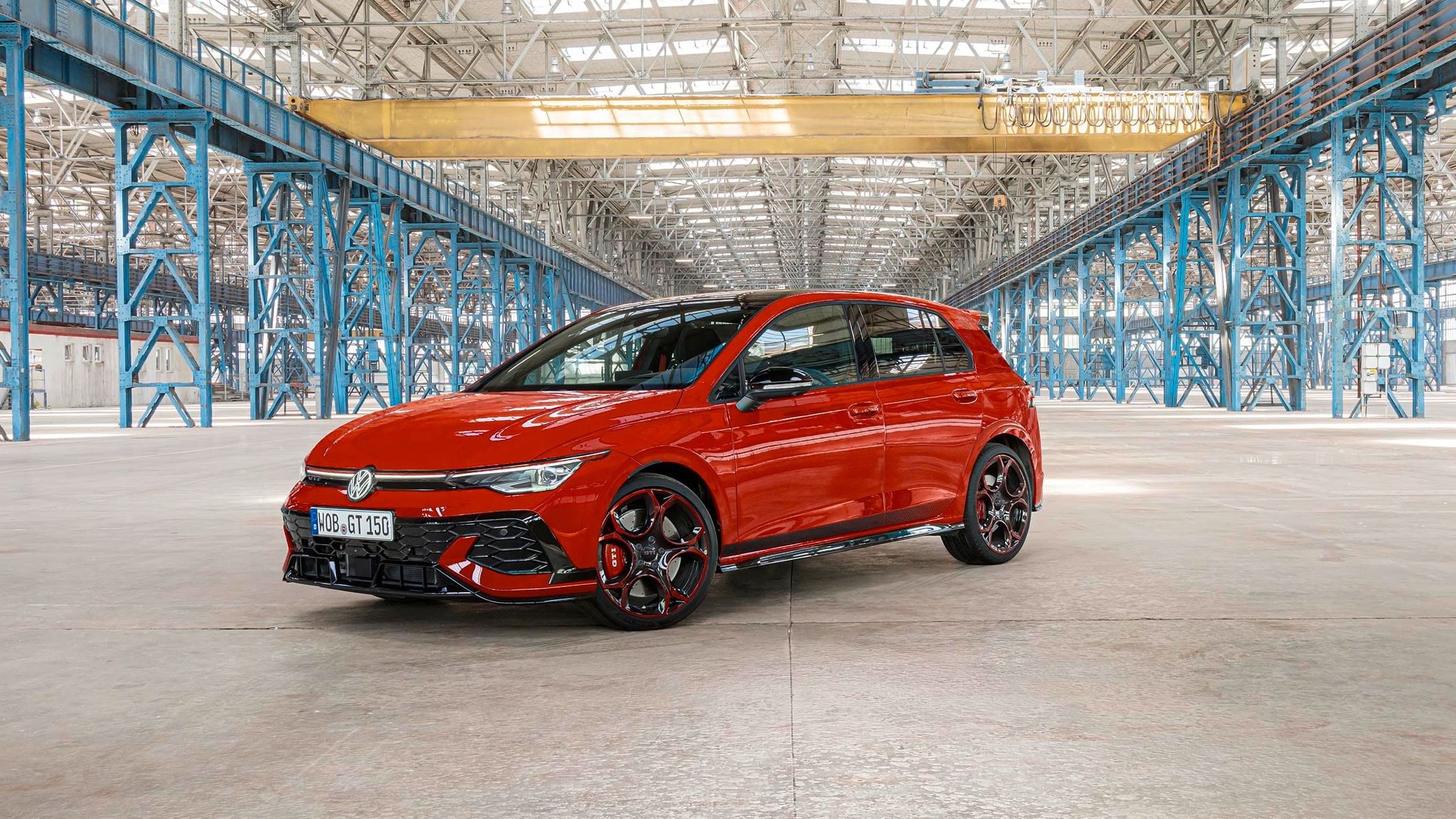 Um VW Golf GTI EDITION 50 vermelho estacionado num pavilhão de fábrica.