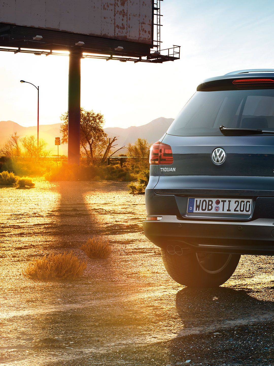 Um carro Tiguan 1 estacionado numa estrada de terra ao pôr-do-sol.