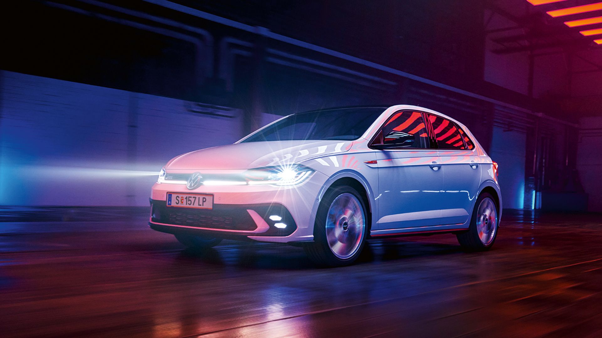 Um VW Polo GTI branco desloca-se no interior de um pavilhão com os faróis LED Matrix ligados e faixa de luzes na dianteira