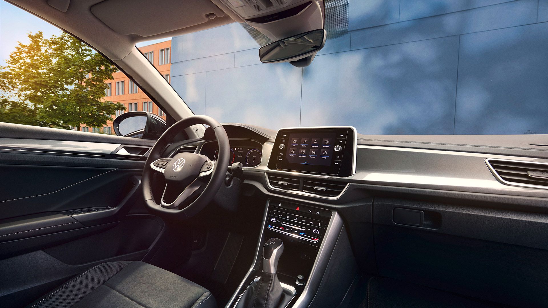 Interior do VW T-Roc, vista do lugar do passageiro para o lugar do condutor e cockpit com volante multifunções e sistema Infotainment