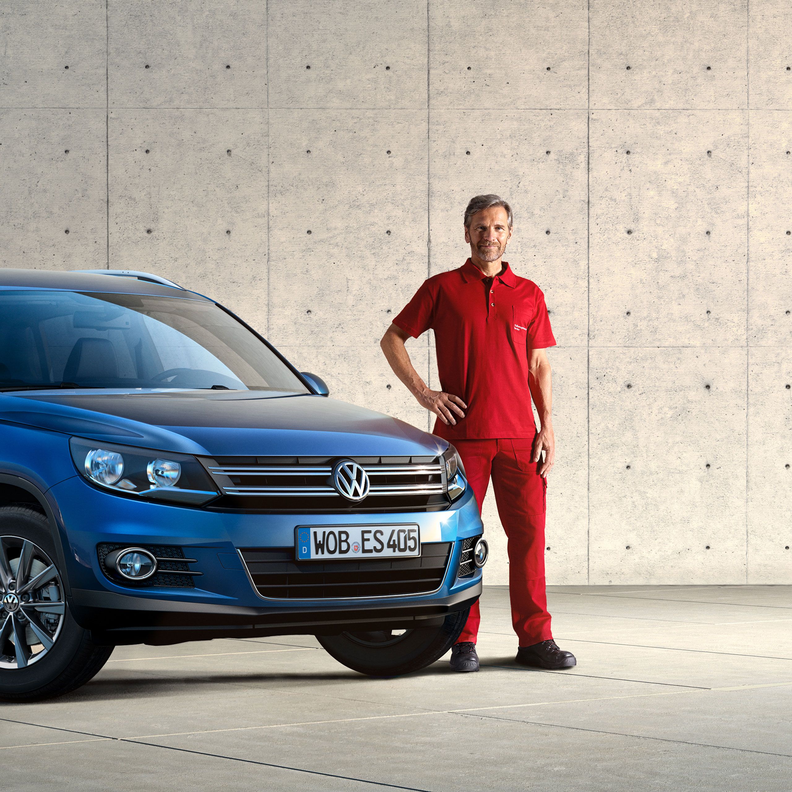 Um empregado do Serviço de Economy ao lado de um Volkswagen Tiguan azul