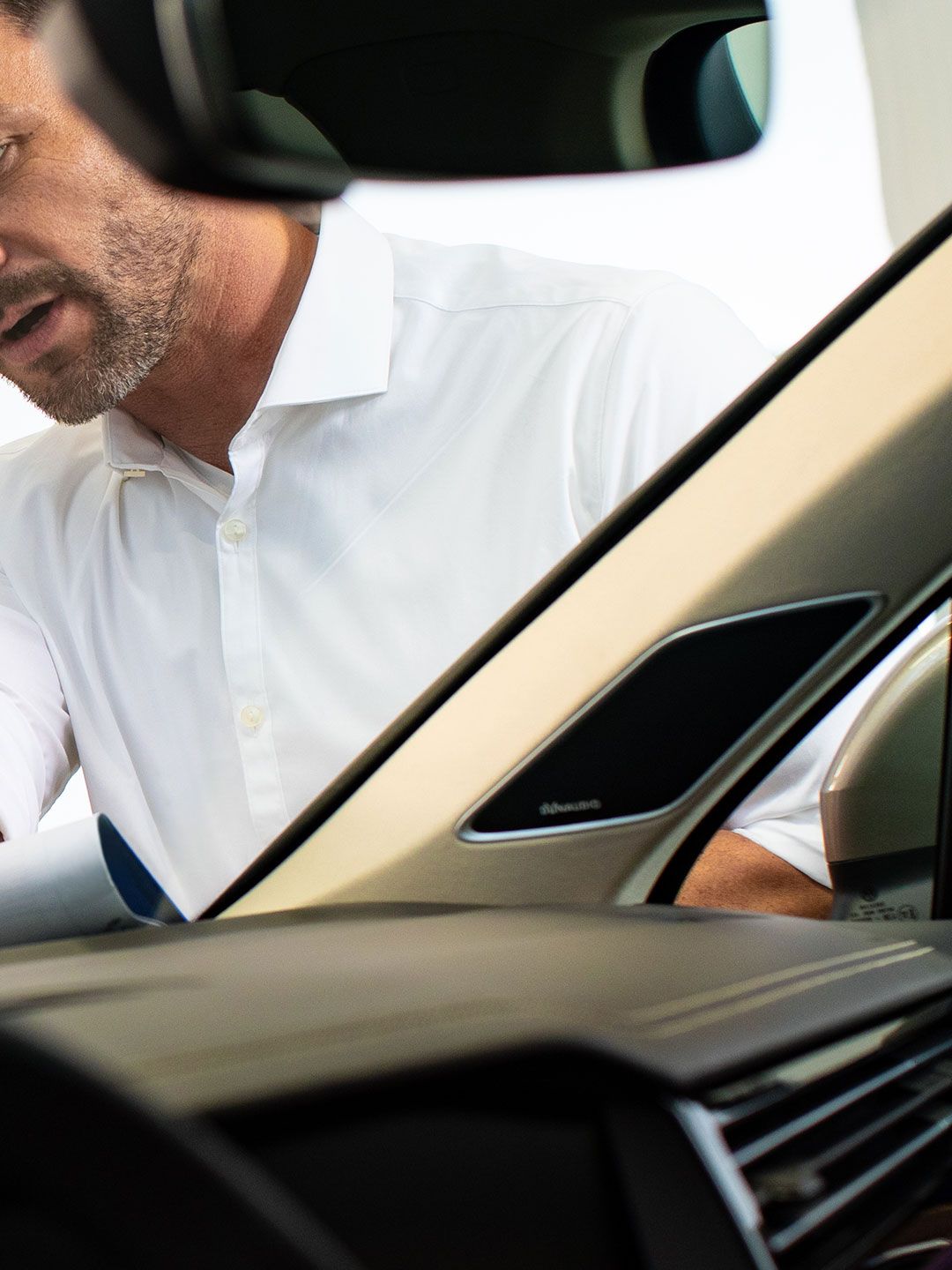 Uma mulher e uma funcionária do serviço VW inspecionam uma marca de uma pedra no para-brisas de um carro Volkswagen
