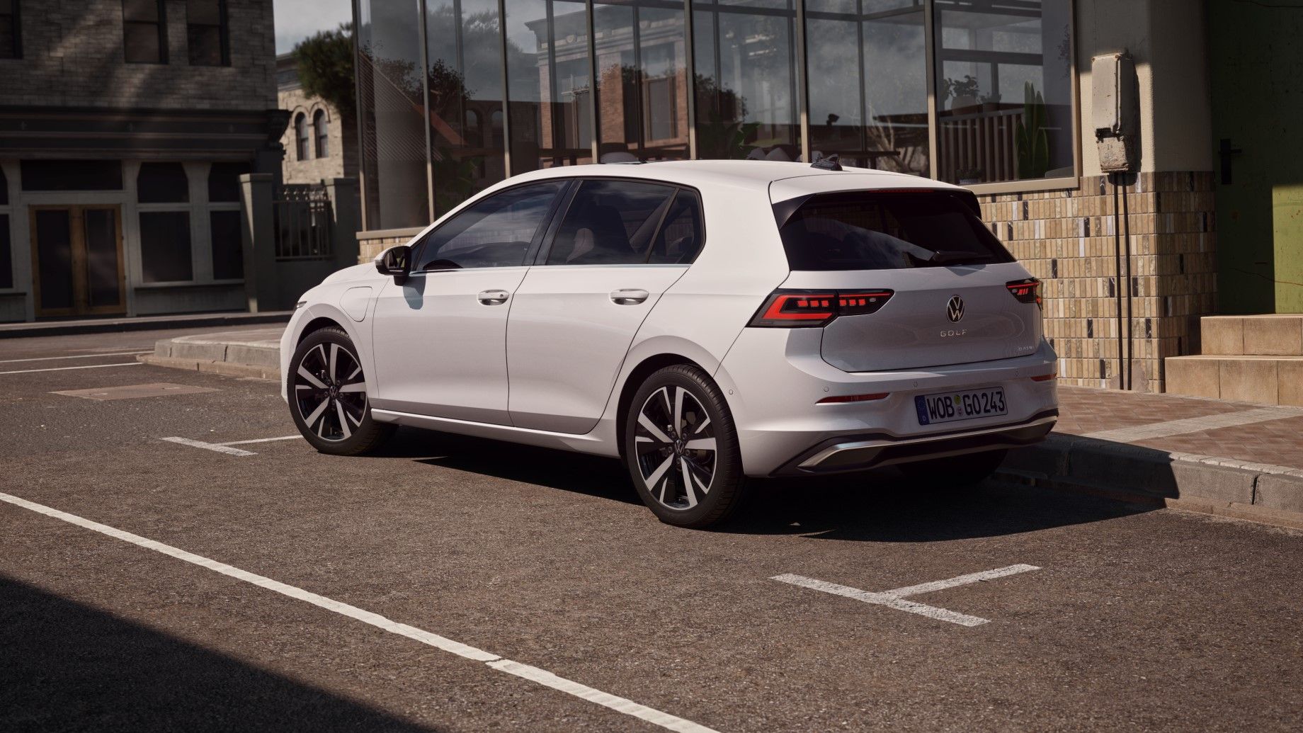 Seitenansicht weißer VW Golf, welches neben einem Restaurant parkt. Ein Mann bewegt sich von der Tür des Restaurants in Richtung des Wagens.