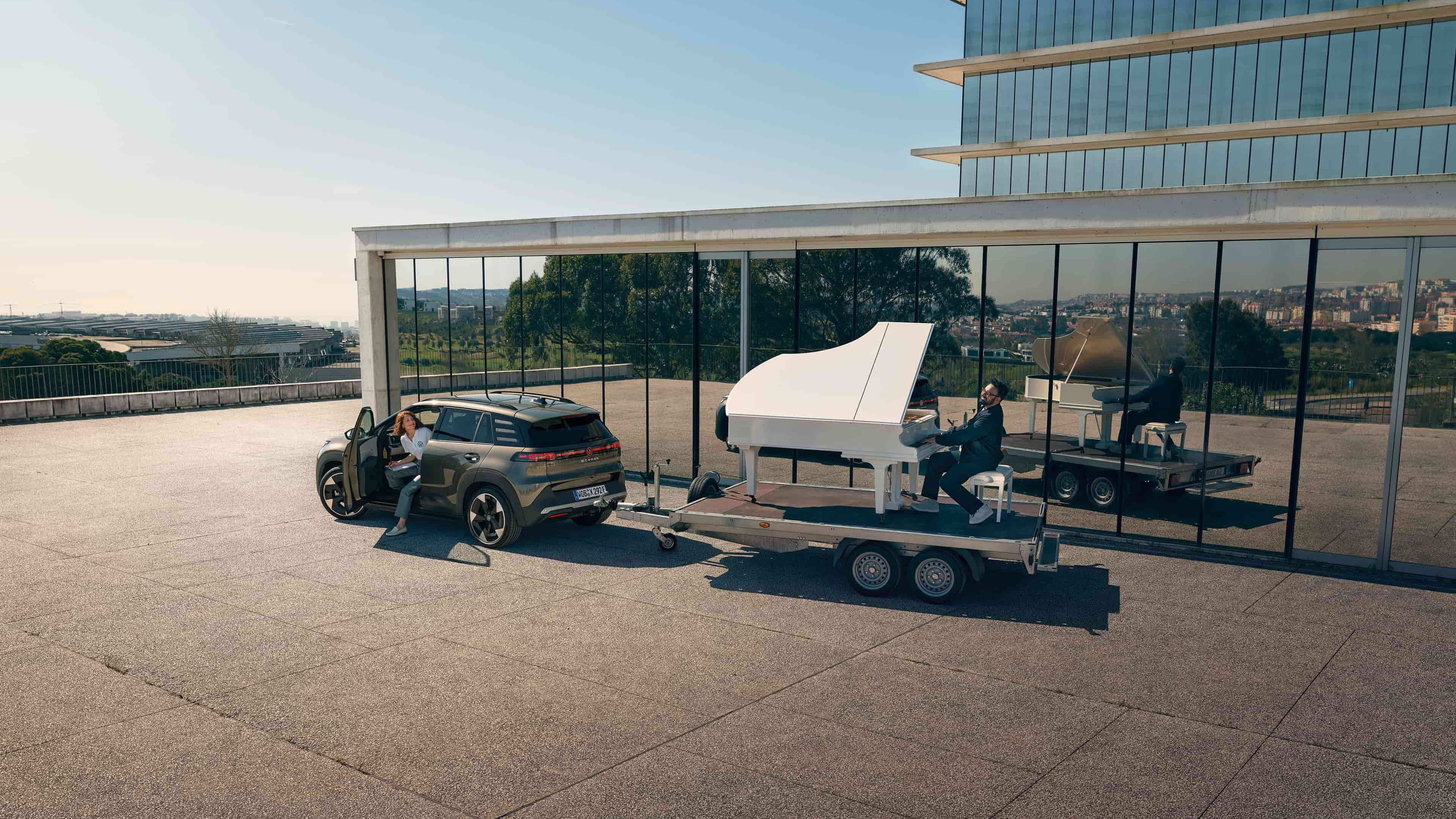 Volkswagen ID. Cross a rebocar um trailer com um homem a tocar piano.