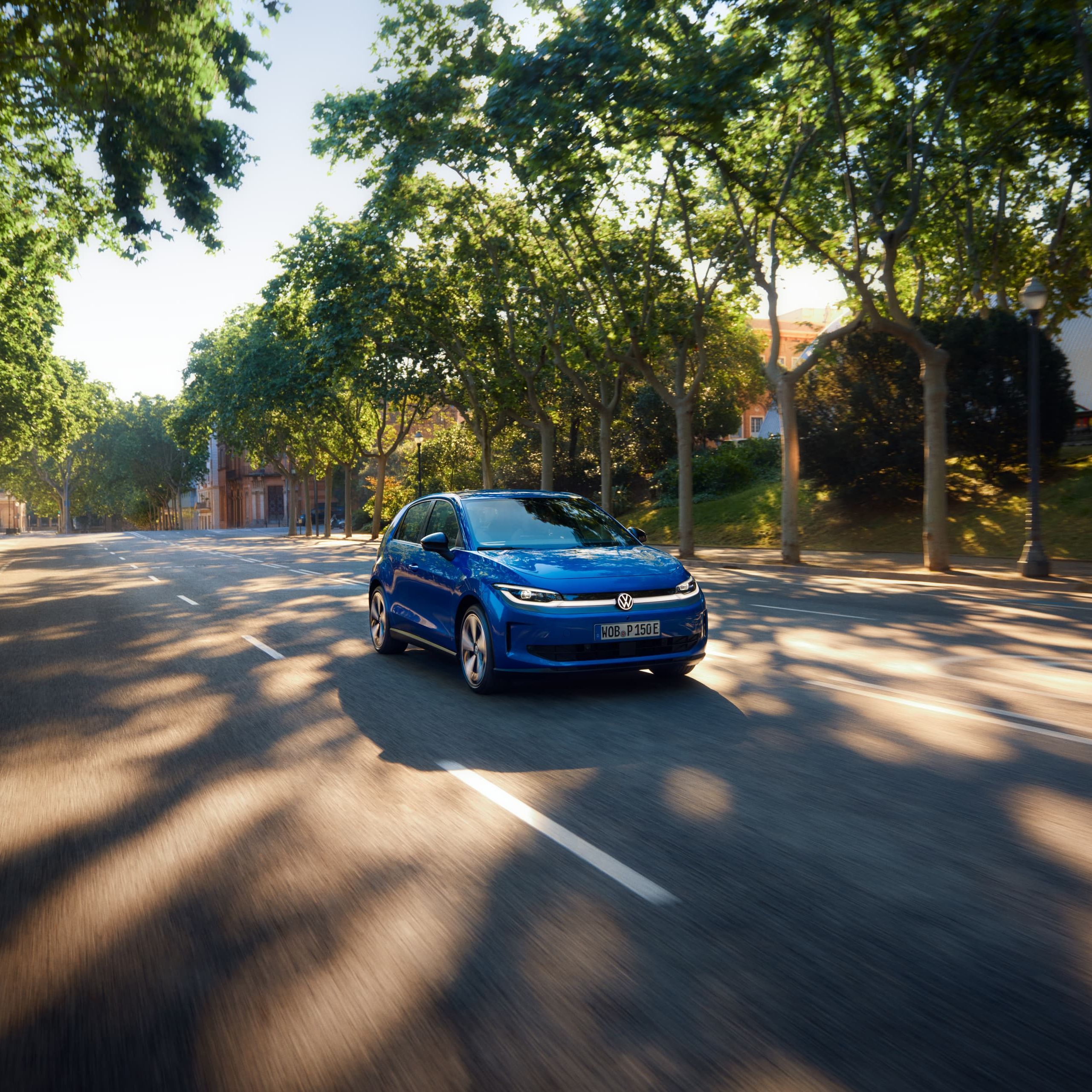 Um VW ID. Polo circula por uma estrada larga, sob a sombra de uma rua arborizada.