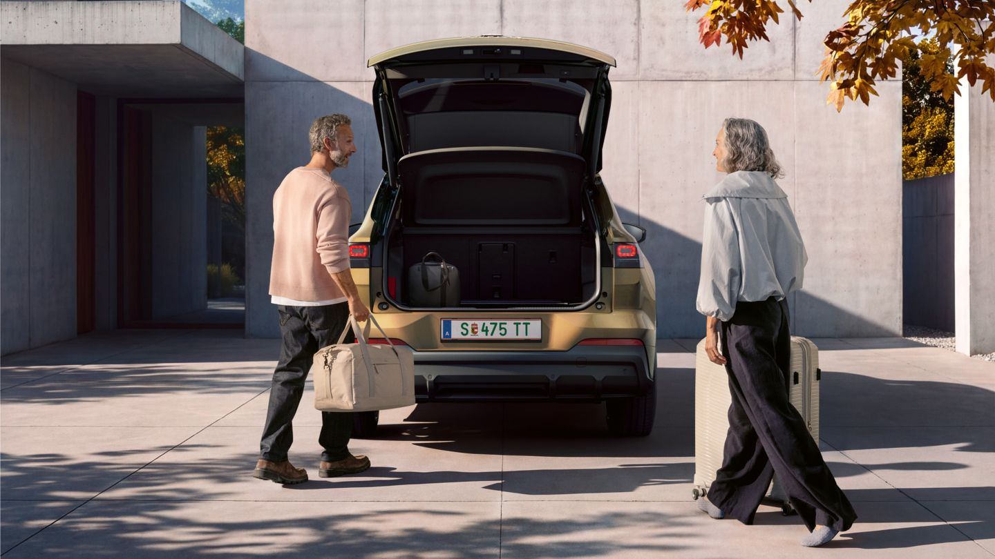 Ein Mann und eine Frau beladen den Kofferraum eines parkenden VW ID.4 Reskin mit Koffern.